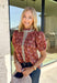 Add a touch of feminine charm to your everyday wardrobe with this beautifully detailed top from Entro. Featuring a rich brown backdrop with a pink floral print, this timeless blouse is full of thoughtful details you'll love. The ruffled neckline creates an effortlessly polished look, while the brown gingham contrast trim adds the perfect pop of classic charm. 