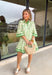 Fresh, timeless, and perfect for spring, this off-white dress by Entro is an easy favorite for sunny days ahead. Featuring a light green floral print throughout, it has a soft, feminine look that feels effortlessly wearable. Dark green trim along the sleeves and hem adds a polished contrast, while the front button details give it a classic touch. Finished with side pockets and a full lining, this dress is comfortable, flattering, and ready for everything from brunch to spring events.