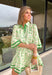 Fresh, timeless, and perfect for spring, this off-white dress by Entro is an easy favorite for sunny days ahead. Featuring a light green floral print throughout, it has a soft, feminine look that feels effortlessly wearable. Dark green trim along the sleeves and hem adds a polished contrast, while the front button details give it a classic touch. Finished with side pockets and a full lining, this dress is comfortable, flattering, and ready for everything from brunch to spring events.