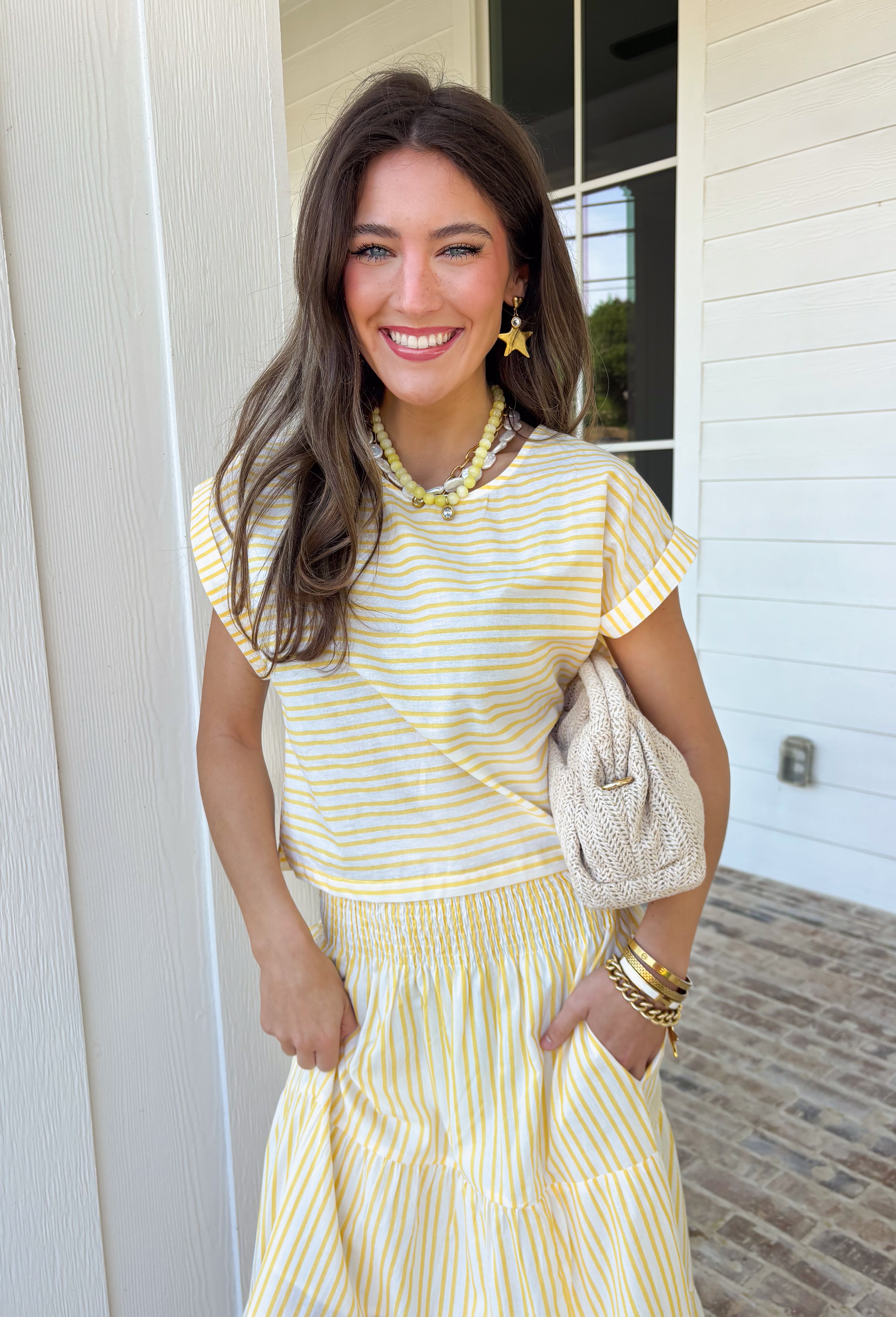 This yellow and white stripe two piece set is bringing all the sunshine to your warm weather wardrobe! The short sleeve top features cuffed sleeves and a subtle keyhole closure for a polished touch, while the matching tiered midi skirt with an elastic waistband keeps things comfortable and flattering. Made from breathable 100% cotton, this set is perfect for warm days filled with brunch plans, baby showers, or weekend outings. 