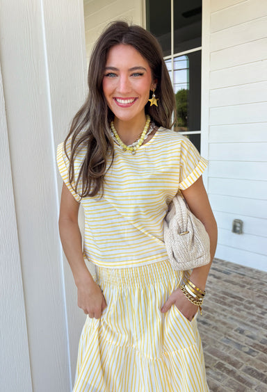 This yellow and white stripe two piece set is bringing all the sunshine to your warm weather wardrobe! The short sleeve top features cuffed sleeves and a subtle keyhole closure for a polished touch, while the matching tiered midi skirt with an elastic waistband keeps things comfortable and flattering. Made from breathable 100% cotton, this set is perfect for warm days filled with brunch plans, baby showers, or weekend outings. 