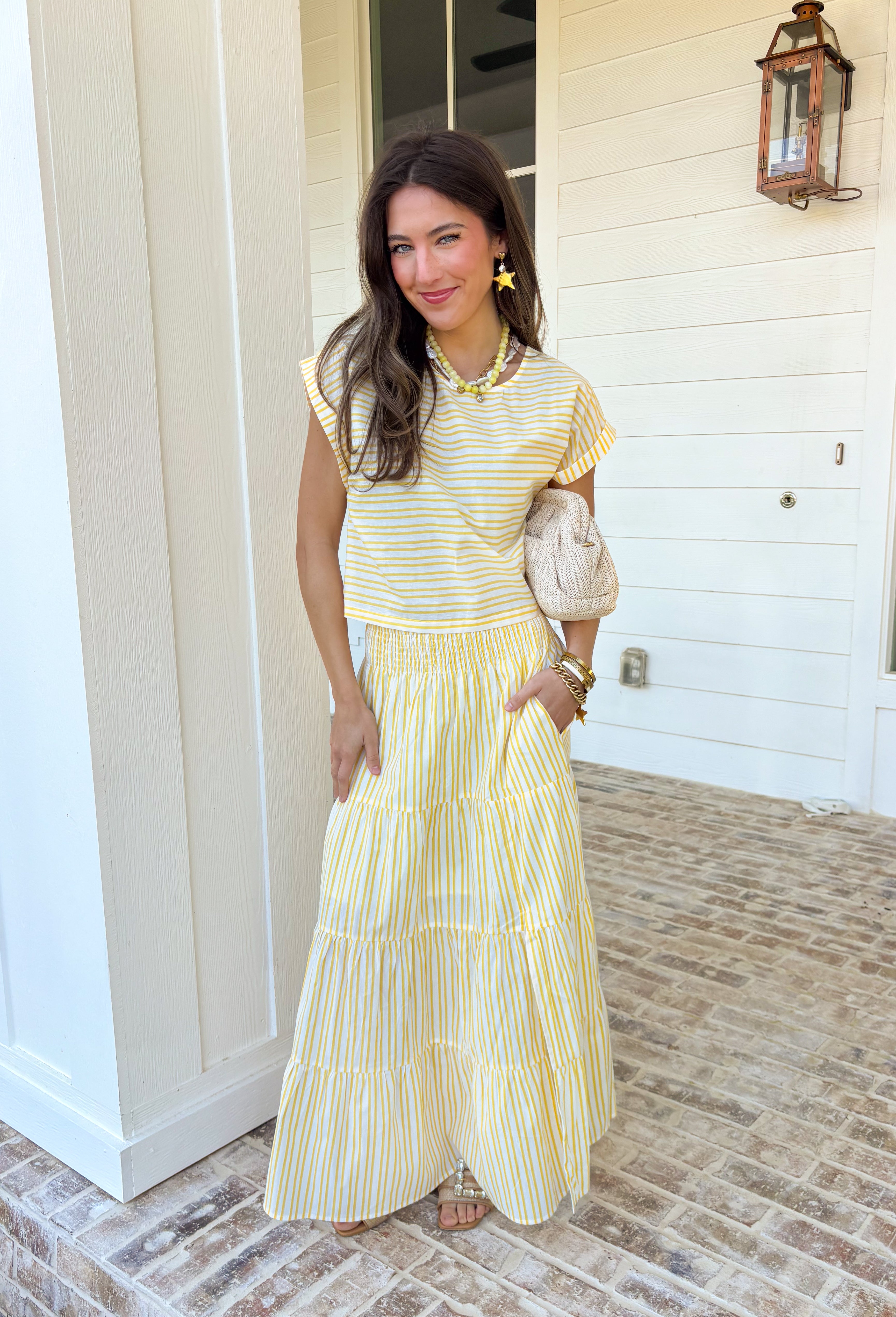 This yellow and white stripe two piece set is bringing all the sunshine to your warm weather wardrobe! The short sleeve top features cuffed sleeves and a subtle keyhole closure for a polished touch, while the matching tiered midi skirt with an elastic waistband keeps things comfortable and flattering. Made from breathable 100% cotton, this set is perfect for warm days filled with brunch plans, baby showers, or weekend outings. 
