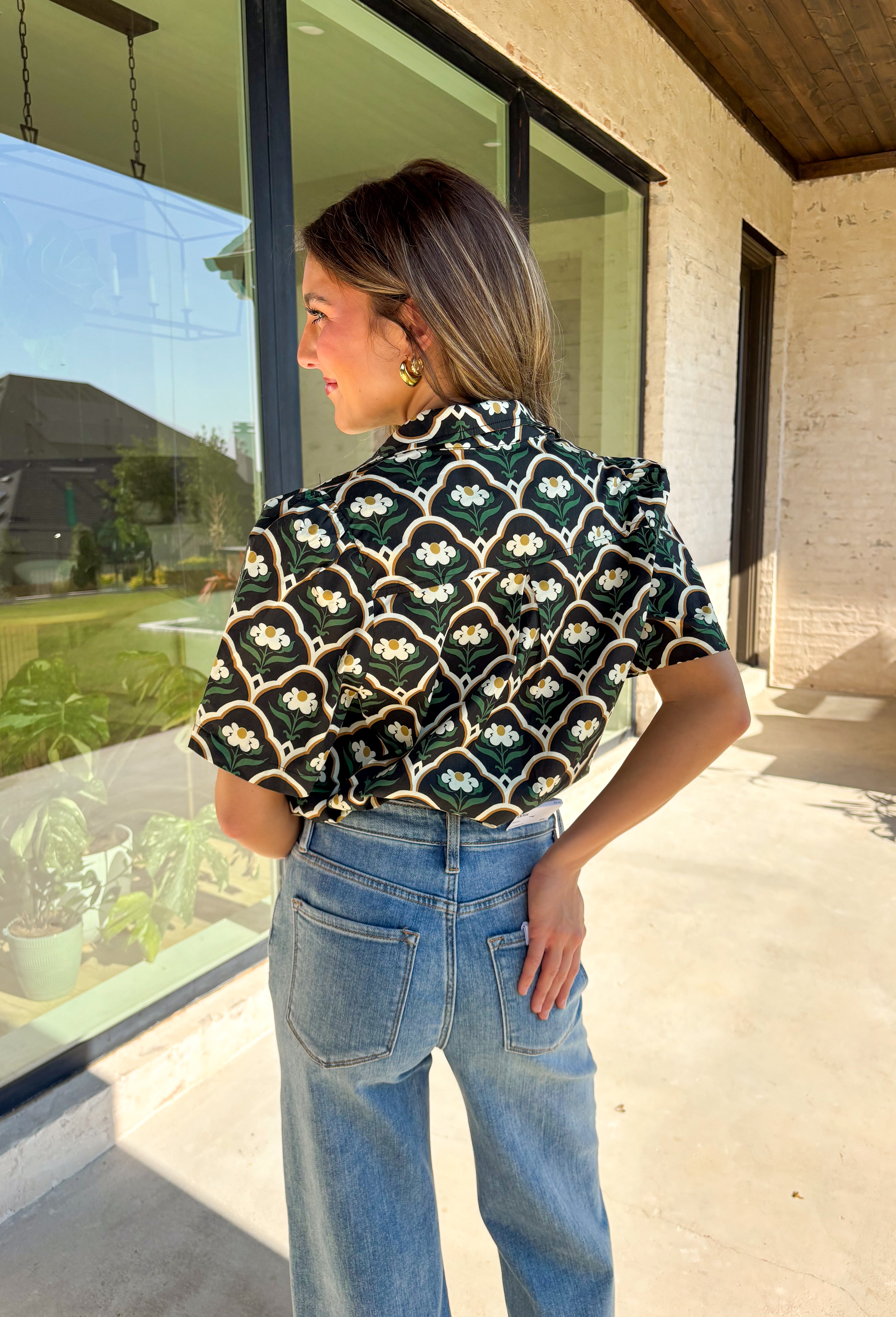 Polished with a hint of romance, this black puff shoulder top is the perfect way to bring fall florals into your wardrobe. The seasonal print in rich, neutral tones pairs beautifully with the structured puff sleeves and high neckline, while a pearl-accent single button closure at the front adds an elegant finishing touch. Crafted with a soft cotton blend and just the right amount of stretch, it’s comfortable enough for all-day wear yet dressy enough for special occasions.