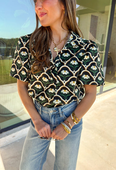 Polished with a hint of romance, this black puff shoulder top is the perfect way to bring fall florals into your wardrobe. The seasonal print in rich, neutral tones pairs beautifully with the structured puff sleeves and high neckline, while a pearl-accent single button closure at the front adds an elegant finishing touch. Crafted with a soft cotton blend and just the right amount of stretch, it’s comfortable enough for all-day wear yet dressy enough for special occasions.