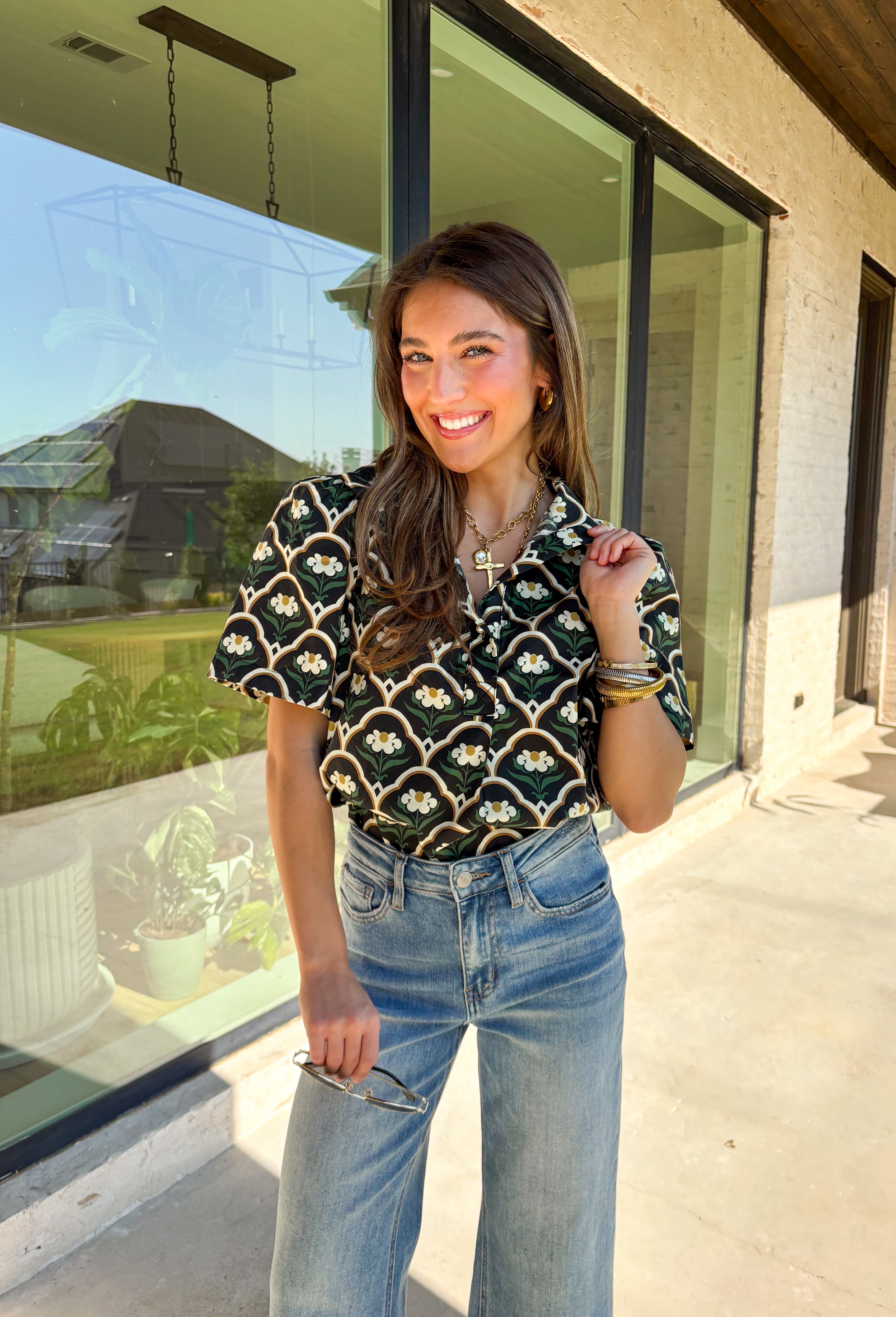 Polished with a hint of romance, this black puff shoulder top is the perfect way to bring fall florals into your wardrobe. The seasonal print in rich, neutral tones pairs beautifully with the structured puff sleeves and high neckline, while a pearl-accent single button closure at the front adds an elegant finishing touch. Crafted with a soft cotton blend and just the right amount of stretch, it’s comfortable enough for all-day wear yet dressy enough for special occasions.