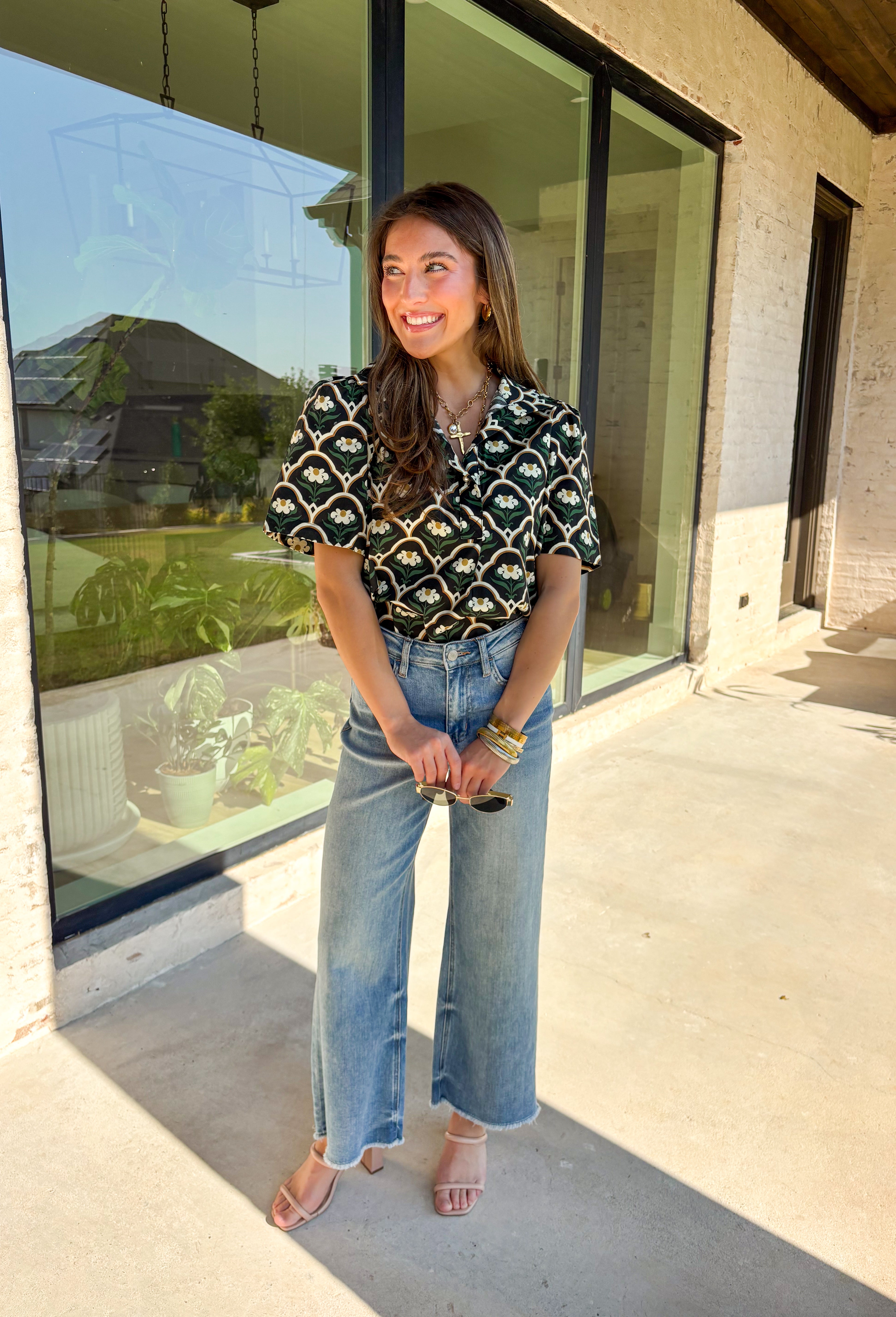 Polished with a hint of romance, this black puff shoulder top is the perfect way to bring fall florals into your wardrobe. The seasonal print in rich, neutral tones pairs beautifully with the structured puff sleeves and high neckline, while a pearl-accent single button closure at the front adds an elegant finishing touch. Crafted with a soft cotton blend and just the right amount of stretch, it’s comfortable enough for all-day wear yet dressy enough for special occasions.