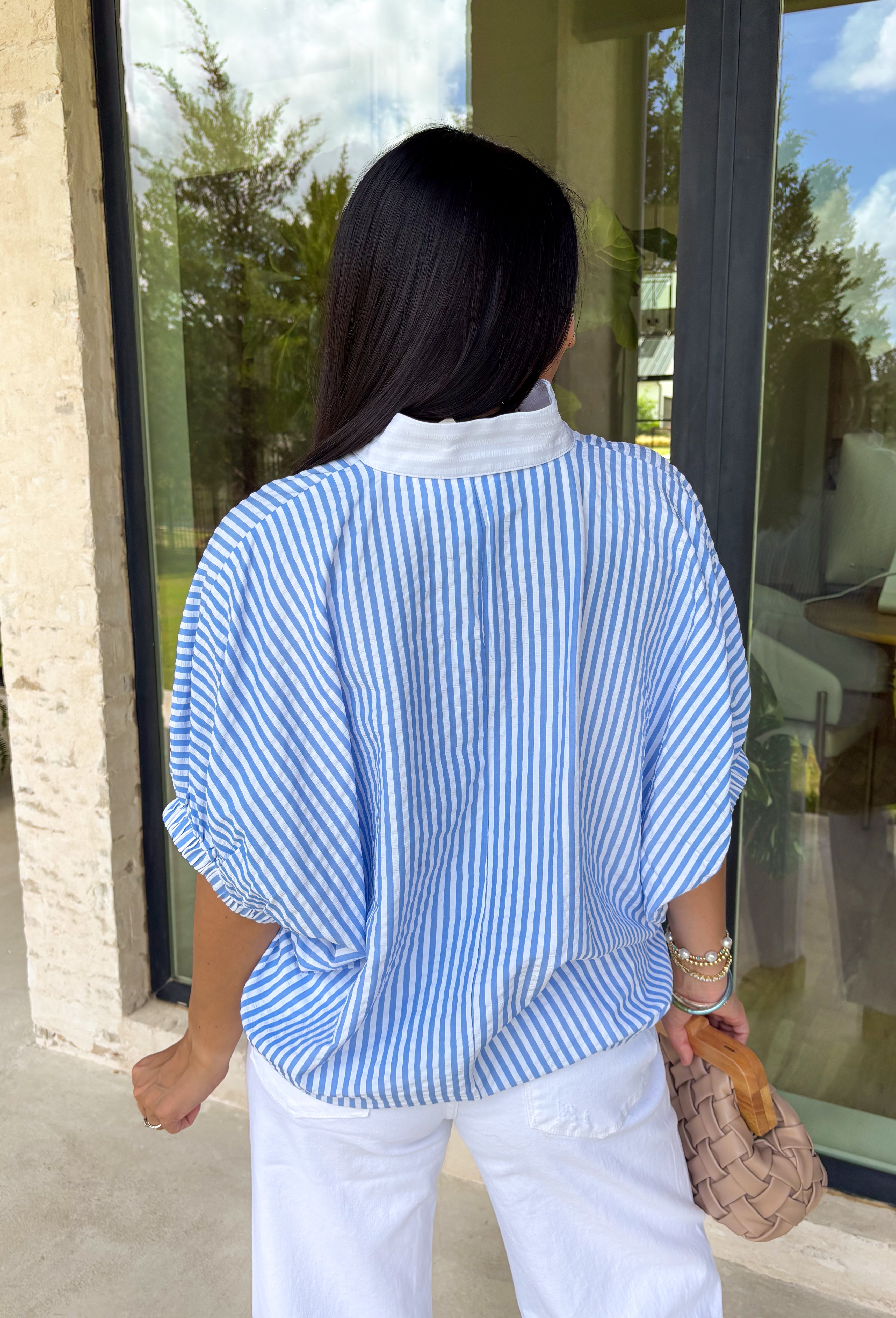 Easy, breezy, and perfect for spring, this blue and white striped short sleeve top by Entro is a go-to for effortless everyday style. The relaxed dolman sleeves give it a laid-back feel, while the contrast V-neck panel adds a clean, eye-catching detail that elevates the look. Lightweight with a soft drape, this top is comfortable, flattering, and made for pairing with your favorite denim or casual bottoms all season long.