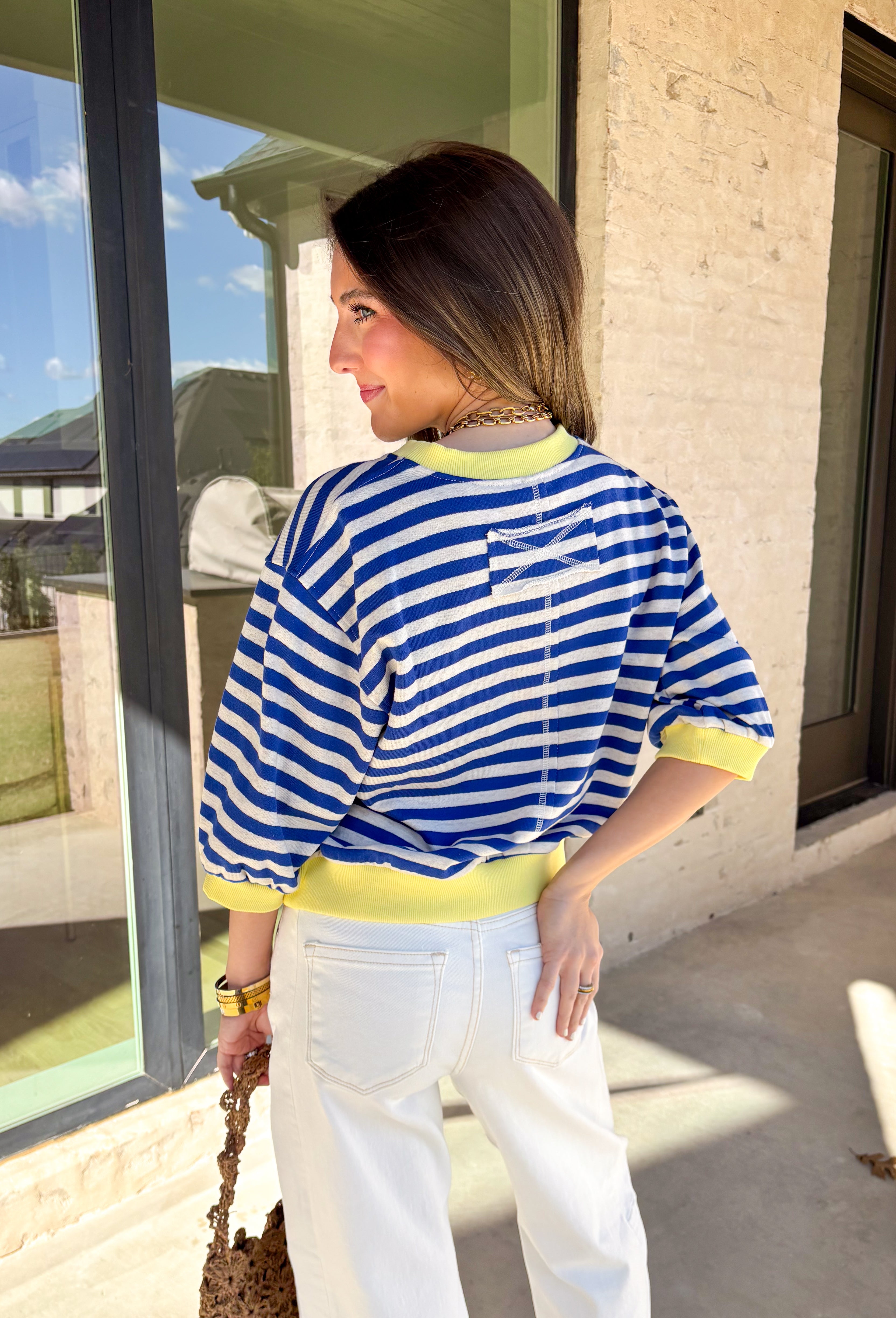 Bright, cheerful, and perfect for spring layering, this blue and off-white striped top by Entro adds a fun pop of color to a classic silhouette. Designed with 3/4 length sleeves, it features sunny yellow accents along the neckline, sleeve cuffs, and hem for a playful contrast that feels fresh and seasonal. Soft and lightweight, this top is easy to wear from casual days to weekend plans.