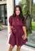 Rich in color and timeless in style, this burgundy dress is the perfect piece to carry you through the fall season. Designed with a classic button-front silhouette, this effortlessly feminine dress features charming puff sleeves and a matching self-tie belt that cinches the waist for a flattering, customizable fit. Side pockets add everyday functionality, while the fully lined cotton fabric keeps you comfortable from morning to night. 