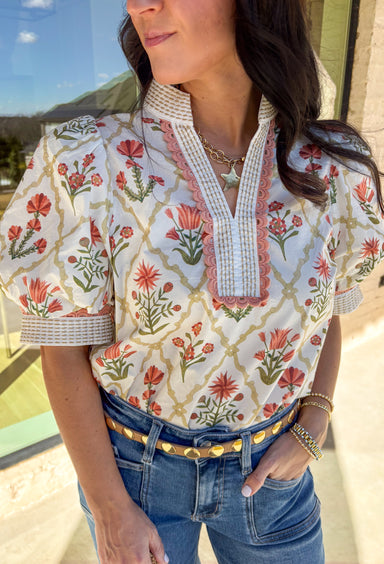 Soft, sweet, and made for spring days, this off-white short sleeve top by Entro is all about the pretty details. Featuring a floral print in salmon and green, it brings a cheerful pop of color while still feeling light and wearable. The salmon scalloped embroidered trim along the front and sleeves adds the cutest finishing touch, and the tan stitching detail gives it that extra bit of texture that makes it feel special. Finished with puff sleeves for a feminine silhouette, this top is perfect for dressing u