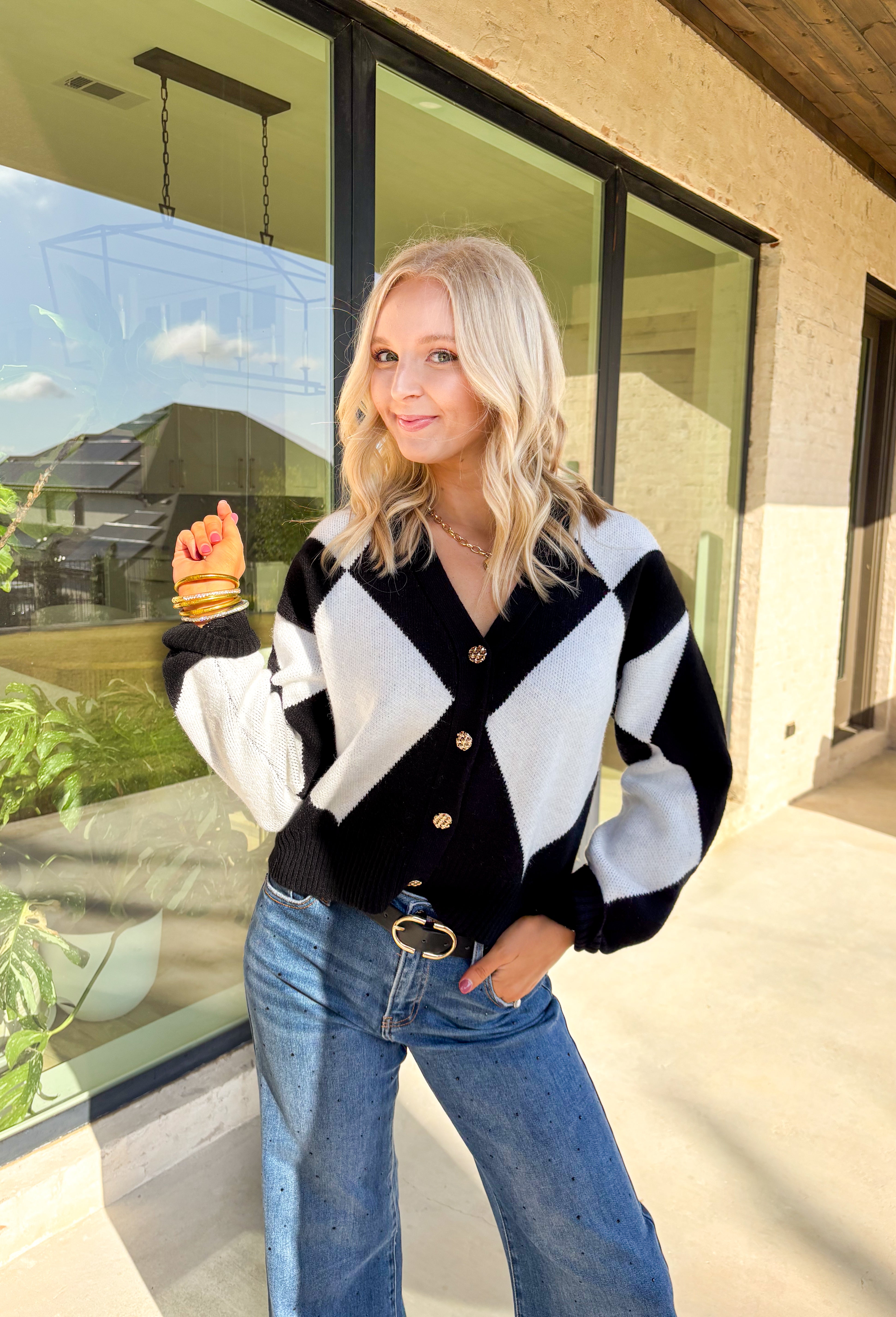 Classic with a cozy twist—this black and white argyle cardigan by On Twelfth is a timeless piece you’ll reach for again and again. The gold textured buttons add a touch of polish, while the soft knit fabric keeps it warm and comfortable for the season. Whether you dress it up or keep it casual, this cardigan brings effortless style to any outfit.