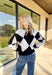 Classic with a cozy twist—this black and white argyle cardigan by On Twelfth is a timeless piece you’ll reach for again and again. The gold textured buttons add a touch of polish, while the soft knit fabric keeps it warm and comfortable for the season. Whether you dress it up or keep it casual, this cardigan brings effortless style to any outfit.
