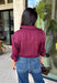 Every wardrobe needs a timeless wine blouse, and this versatile top from Entro is one you'll reach for again and again. Designed with a flattering v-neckline and button-front closure, this effortlessly polished piece transitions seamlessly from workdays to weekends. The ¾ roll-tab sleeves offer versatile styling, while the elasticized smocked back hem creates a comfortable fit with a modern touch. 
