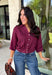 Every wardrobe needs a timeless wine blouse, and this versatile top from Entro is one you'll reach for again and again. Designed with a flattering v-neckline and button-front closure, this effortlessly polished piece transitions seamlessly from workdays to weekends. The ¾ roll-tab sleeves offer versatile styling, while the elasticized smocked back hem creates a comfortable fit with a modern touch. 