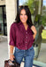 Every wardrobe needs a timeless wine blouse, and this versatile top from Entro is one you'll reach for again and again. Designed with a flattering v-neckline and button-front closure, this effortlessly polished piece transitions seamlessly from workdays to weekends. The ¾ roll-tab sleeves offer versatile styling, while the elasticized smocked back hem creates a comfortable fit with a modern touch. 
