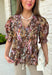 Bring a touch of timeless charm to your fall wardrobe with this beautifully detailed floral blouse. Designed in a warm brown hue with a soft neutral floral print, this top is the perfect blend of feminine and effortless. Delicate pintuck detailing, a flattering v-neckline, and button-front accents create a polished look, while the puff sleeves with smocked ruffle cuffs add just the right amount of romantic flair. 
