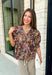 Bring a touch of timeless charm to your fall wardrobe with this beautifully detailed floral blouse. Designed in a warm brown hue with a soft neutral floral print, this top is the perfect blend of feminine and effortless. Delicate pintuck detailing, a flattering v-neckline, and button-front accents create a polished look, while the puff sleeves with smocked ruffle cuffs add just the right amount of romantic flair. 