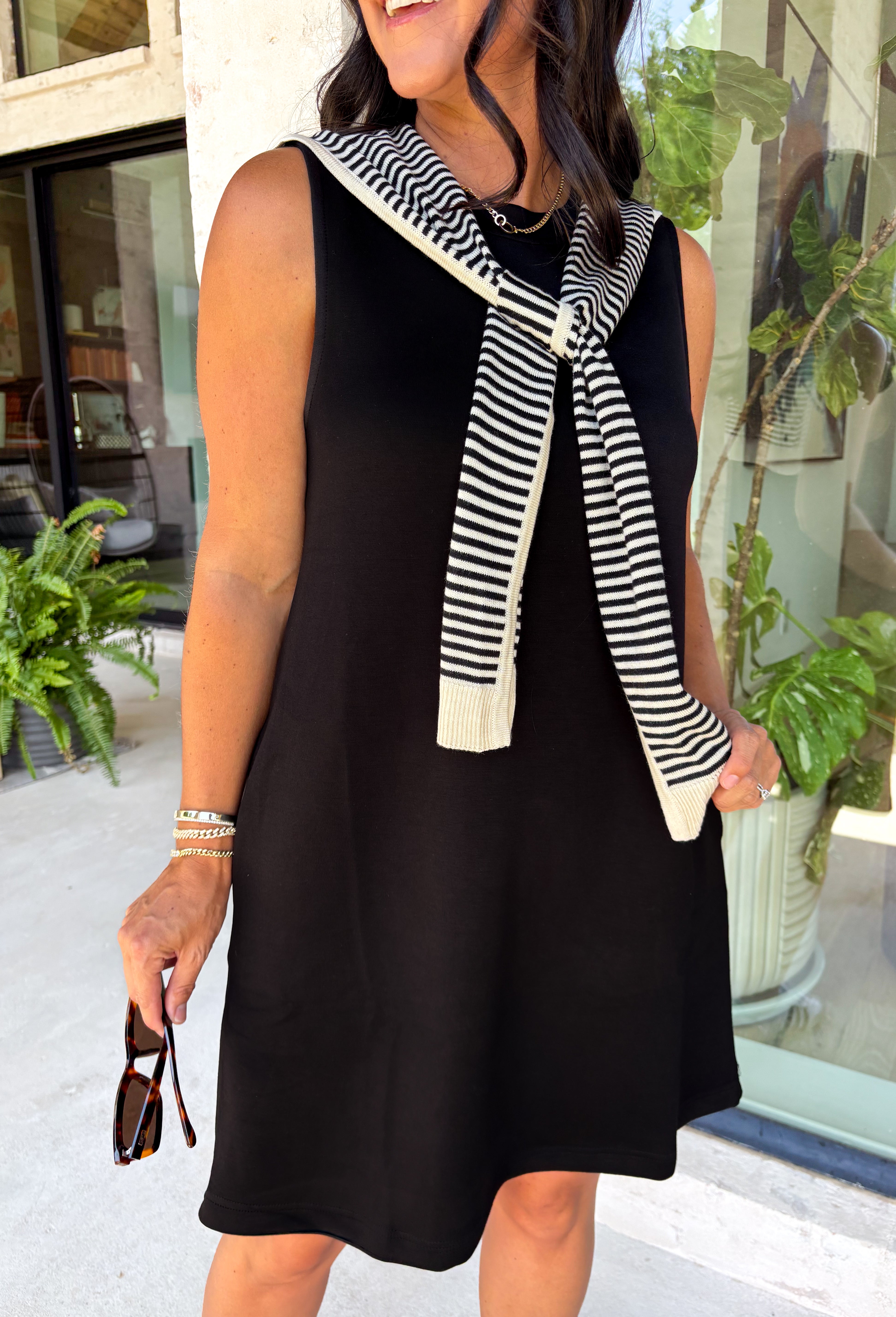 The layered look has never been easier! This black knit mini dress features an attached black and white striped sweater scarf detail, giving you the cozy, elevated style of layered fall fashion in one effortless piece. Crafted from a soft, comfortable knit, it's perfect for crisp autumn days when you want to look polished without sacrificing comfort. From brunch dates and shopping trips to dinner with friends, this chic dress is ready for every fall occasion.
