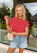 Nothing says “easy spring outfit” like a classic red-and-white stripe moment! This short sleeve top is one of those throw-on-and-go pieces that instantly looks cute without even trying. The bright red base feels fun and fresh for the season, while the crisp white stripes keep it timeless. Finished with elastic sleeve cuffs for a soft, slightly puffed shape, it’s comfy enough for all-day wear and polished enough to dress up with your favorite denim and accessories.