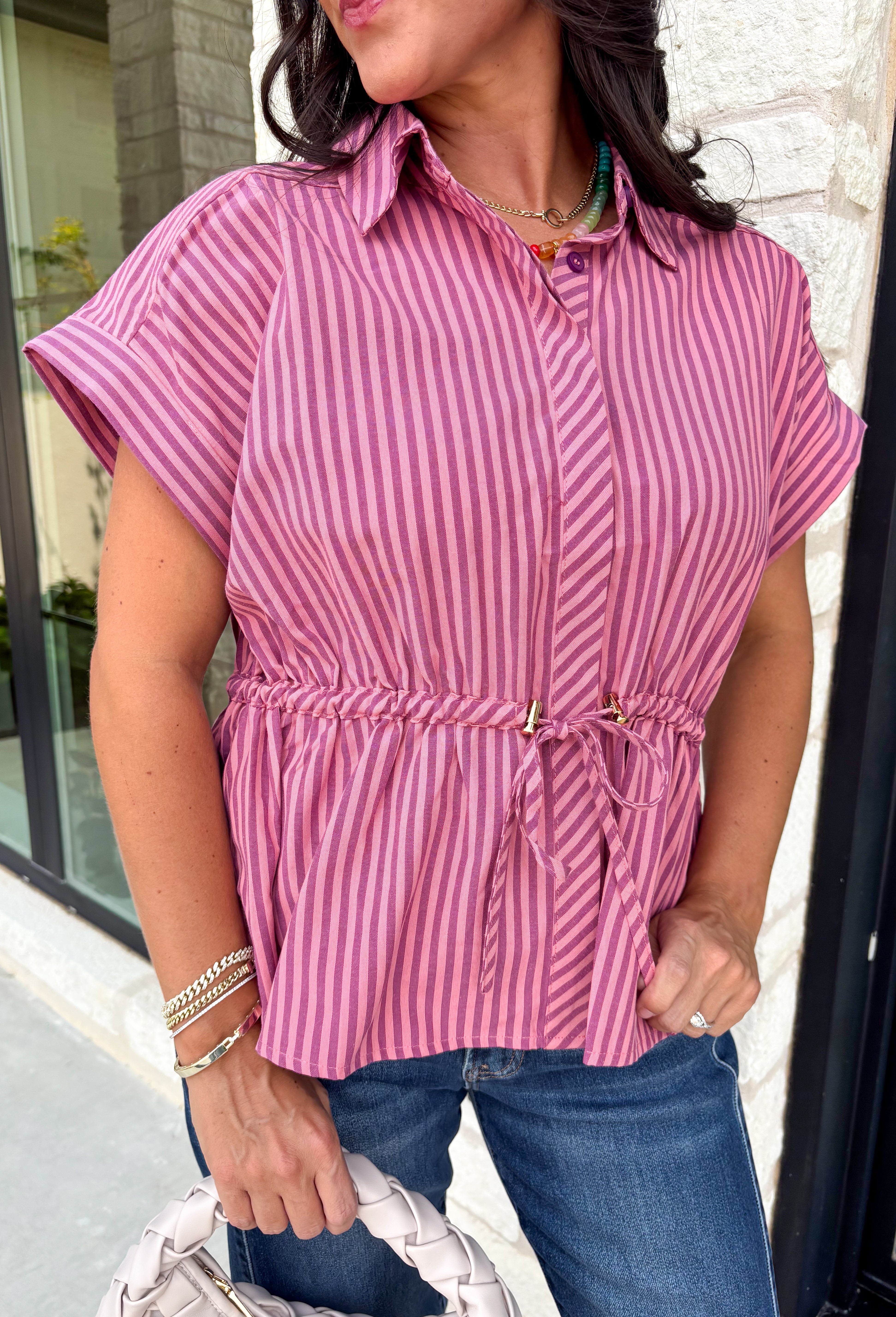 Classic stripes get a flattering update with this effortlessly stylish top that's perfect for the season! Designed in a rich marsala hue with timeless stripe detailing, this lightweight blouse is easy to dress up or down for wherever your day takes you. The adjustable drawstring waist and gathered back create a figure-flattering silhouette, while the button-front design adds a polished finish. 