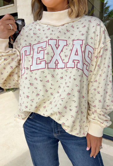 Cute, cozy, and full of Texas charm! This cream mock neck pullover features a dainty pink floral print with “TEXAS” across the front in white outlined in pink for the sweetest statement. It’s the perfect mix of feminine and hometown pride. The soft fabric and relaxed fit make it easy to wear all day, whether you’re running errands, heading to a game, or just keeping things comfy. The mock neck adds a slightly elevated touch while still feeling laid-back and cozy.