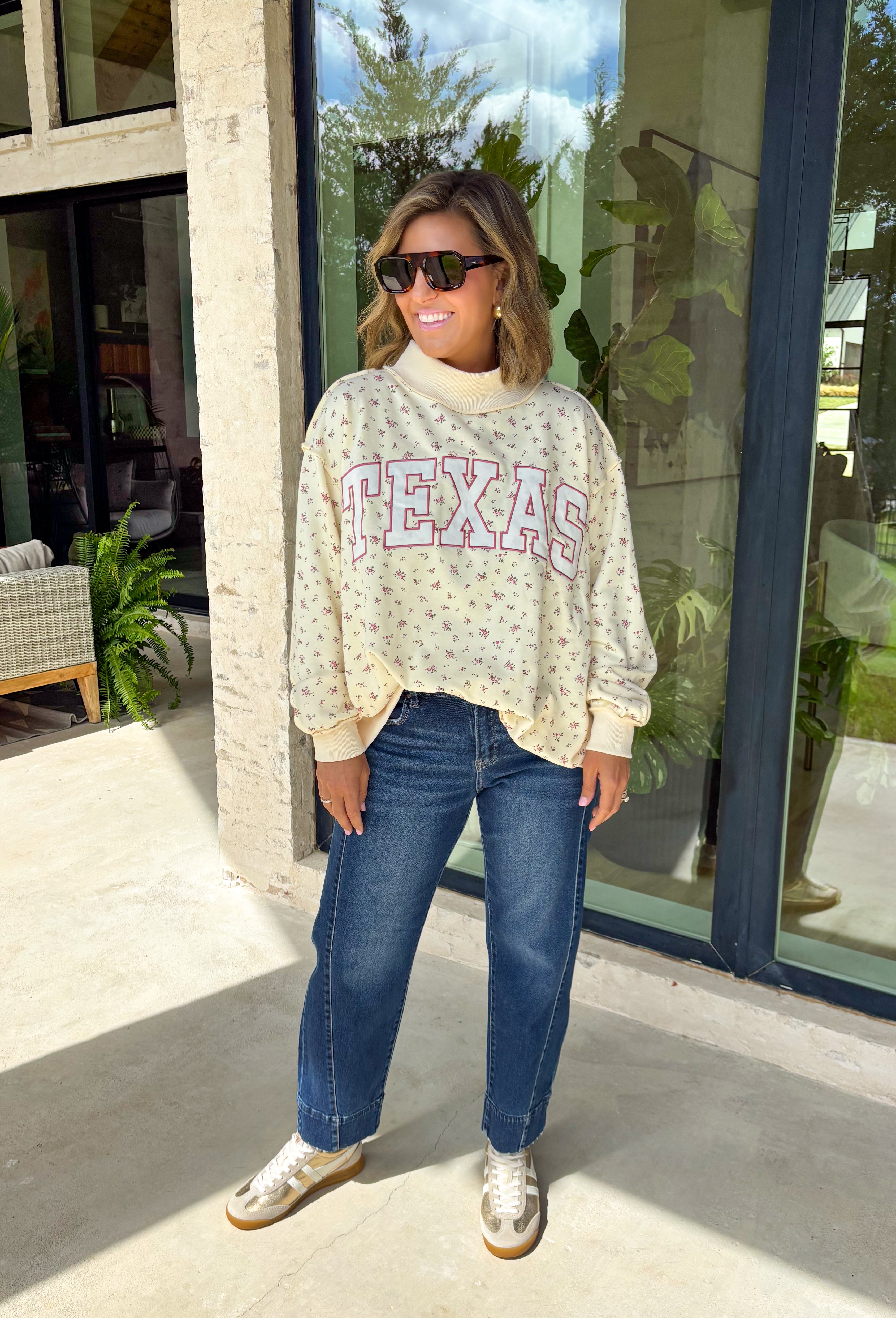 Cute, cozy, and full of Texas charm! This cream mock neck pullover features a dainty pink floral print with “TEXAS” across the front in white outlined in pink for the sweetest statement. It’s the perfect mix of feminine and hometown pride. The soft fabric and relaxed fit make it easy to wear all day, whether you’re running errands, heading to a game, or just keeping things comfy. The mock neck adds a slightly elevated touch while still feeling laid-back and cozy.