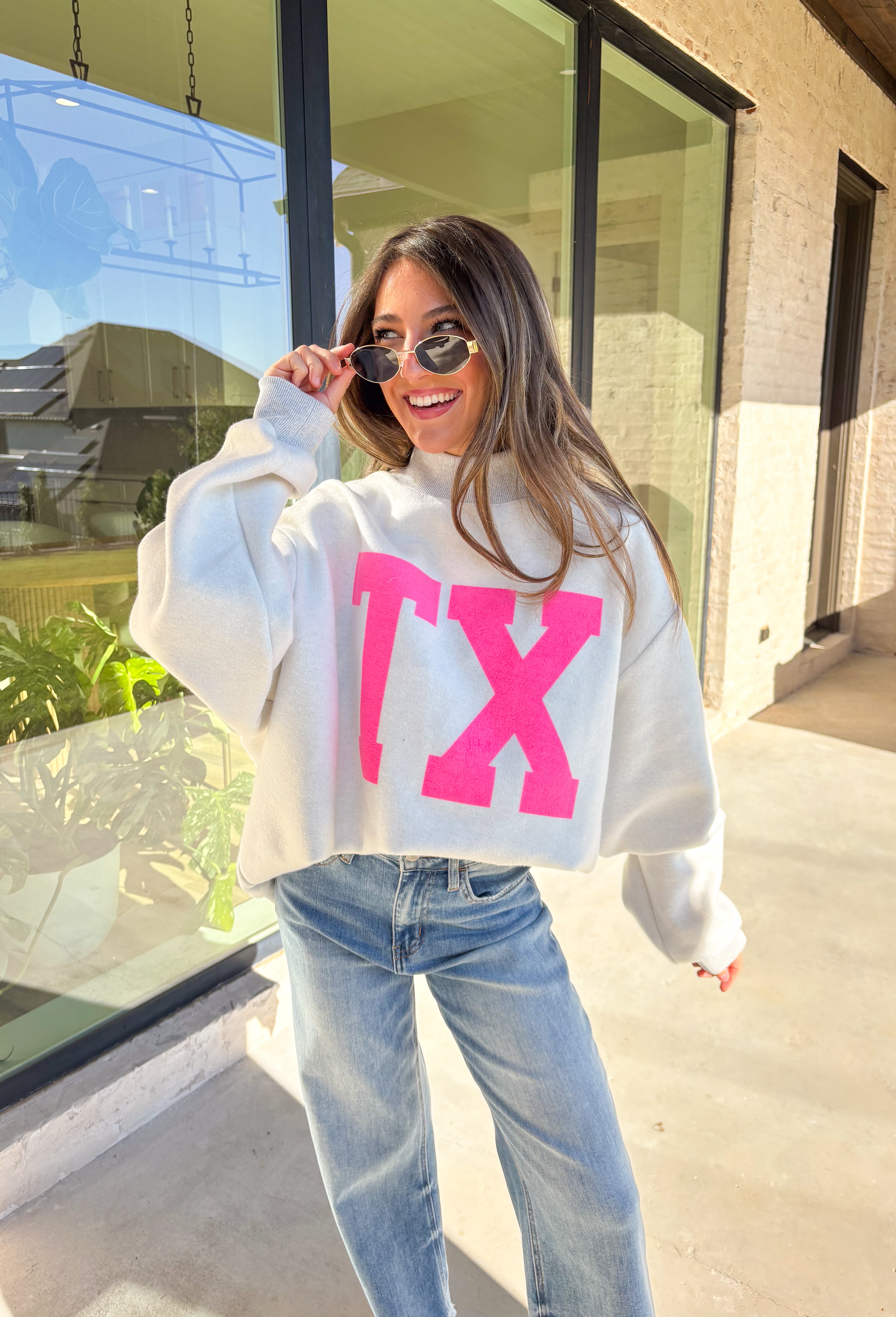 Show your Lone Star pride in this cozy reversible pullover by Bucket List! Crafted from soft fleece, this heather gray mock neck sweatshirt offers two fun looks in one—one side reads “Texas” in bold black lettering, while the reverse features “TX” in bright hot pink. Warm, comfy, and effortlessly cool, it’s perfect for everything from game days to laid-back weekends.