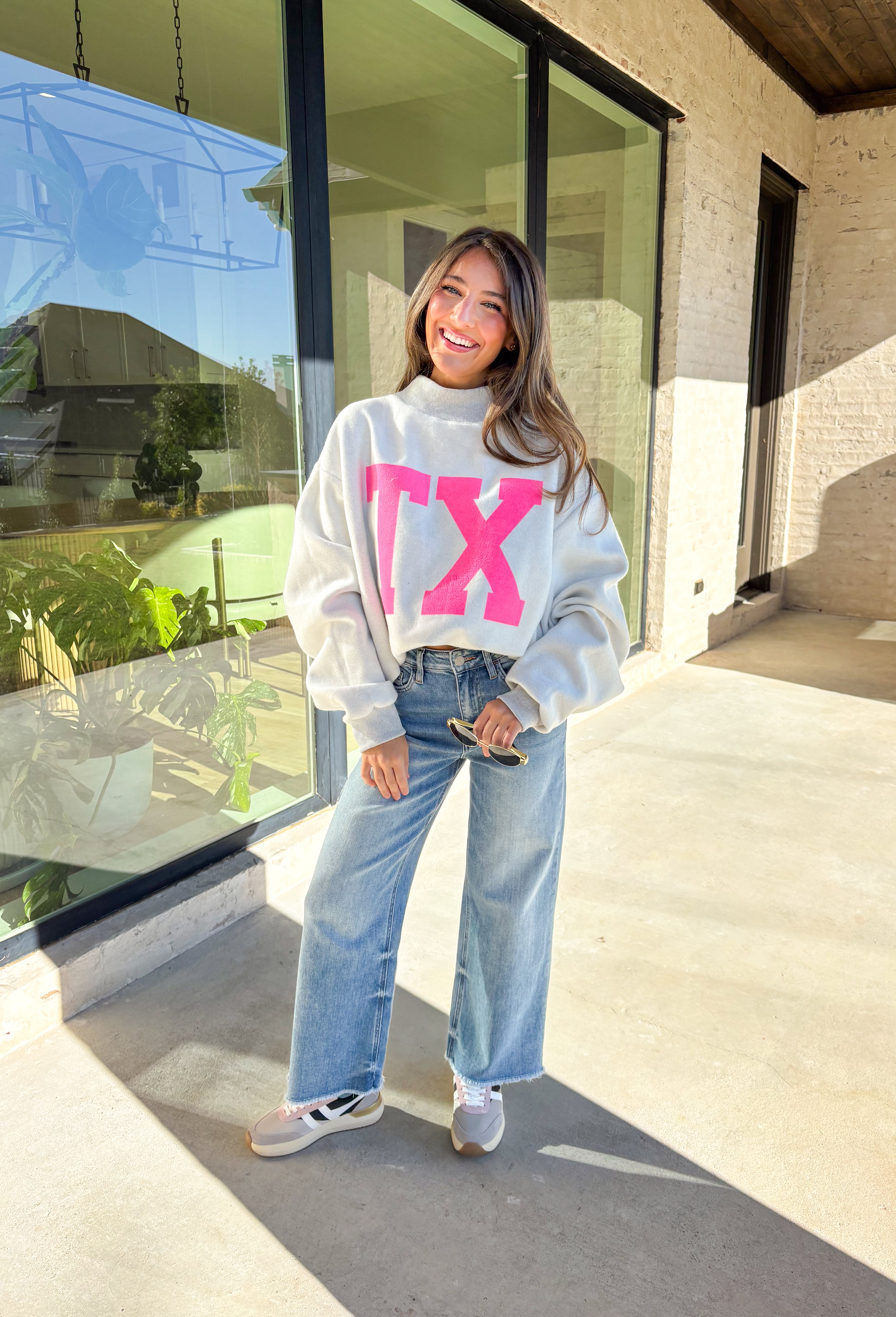 Show your Lone Star pride in this cozy reversible pullover by Bucket List! Crafted from soft fleece, this heather gray mock neck sweatshirt offers two fun looks in one—one side reads “Texas” in bold black lettering, while the reverse features “TX” in bright hot pink. Warm, comfy, and effortlessly cool, it’s perfect for everything from game days to laid-back weekends.
