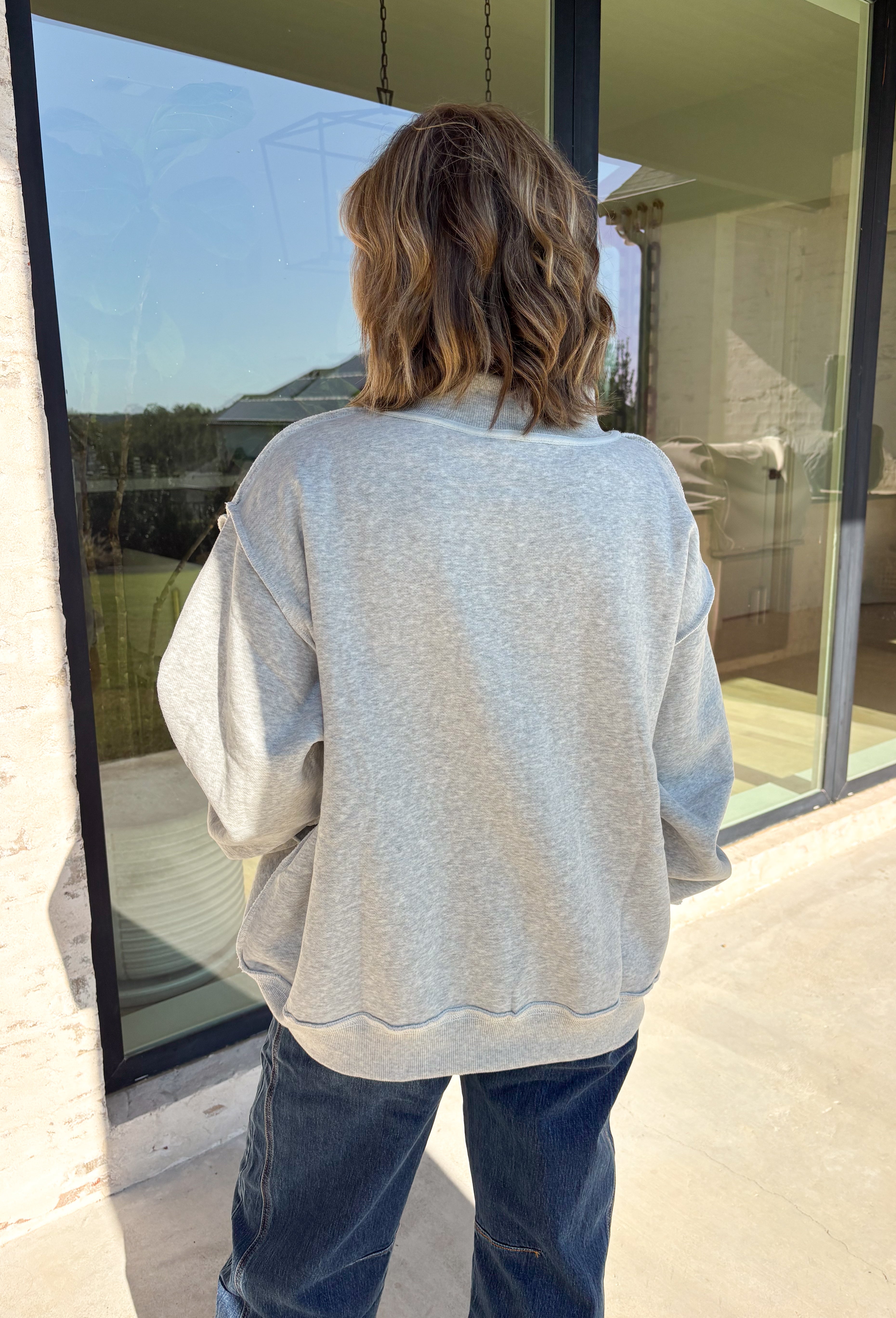 Show a little Lone Star love while staying extra cozy in this heather grey “Texas” pullover from Bucket List. The bold lettering features a crimson and white stripe print, with each letter outlined in white embroidery for added texture and a standout finish. A mock neckline and long sleeves give it a cozy cold-weather feel, while the fleece-lined interior makes it perfect for crisp fall mornings and chilly weekends. 