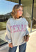 Show a little Lone Star love while staying extra cozy in this heather grey “Texas” pullover from Bucket List. The bold lettering features a crimson and white stripe print, with each letter outlined in white embroidery for added texture and a standout finish. A mock neckline and long sleeves give it a cozy cold-weather feel, while the fleece-lined interior makes it perfect for crisp fall mornings and chilly weekends. 