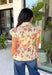 Fresh florals meet cozy fall style in this charming peplum blouse. Featuring a soft neutral backdrop with delicate pops of pink and green, this top brings just the right amount of color to your autumn wardrobe. The collared neckline and button front add a timeless, polished touch, while the peplum hem creates a flattering silhouette you'll love. Elastic puff sleeves complete the look with feminine charm, making this top perfect for everything from workdays to weekend brunches.