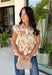 Fresh florals meet cozy fall style in this charming peplum blouse. Featuring a soft neutral backdrop with delicate pops of pink and green, this top brings just the right amount of color to your autumn wardrobe. The collared neckline and button front add a timeless, polished touch, while the peplum hem creates a flattering silhouette you'll love. Elastic puff sleeves complete the look with feminine charm, making this top perfect for everything from workdays to weekend brunches.