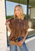 Elevate your fall wardrobe with this stunning faux leather top that perfectly blends edgy style with feminine charm. Designed in a rich chocolate brown, this statement piece features beautiful lace detailing along the front that softens the sleek faux leather finish for a look that's effortlessly sophisticated. The textured fabric adds depth and dimension, while the classic short sleeve silhouette makes it easy to style from season to season. 
