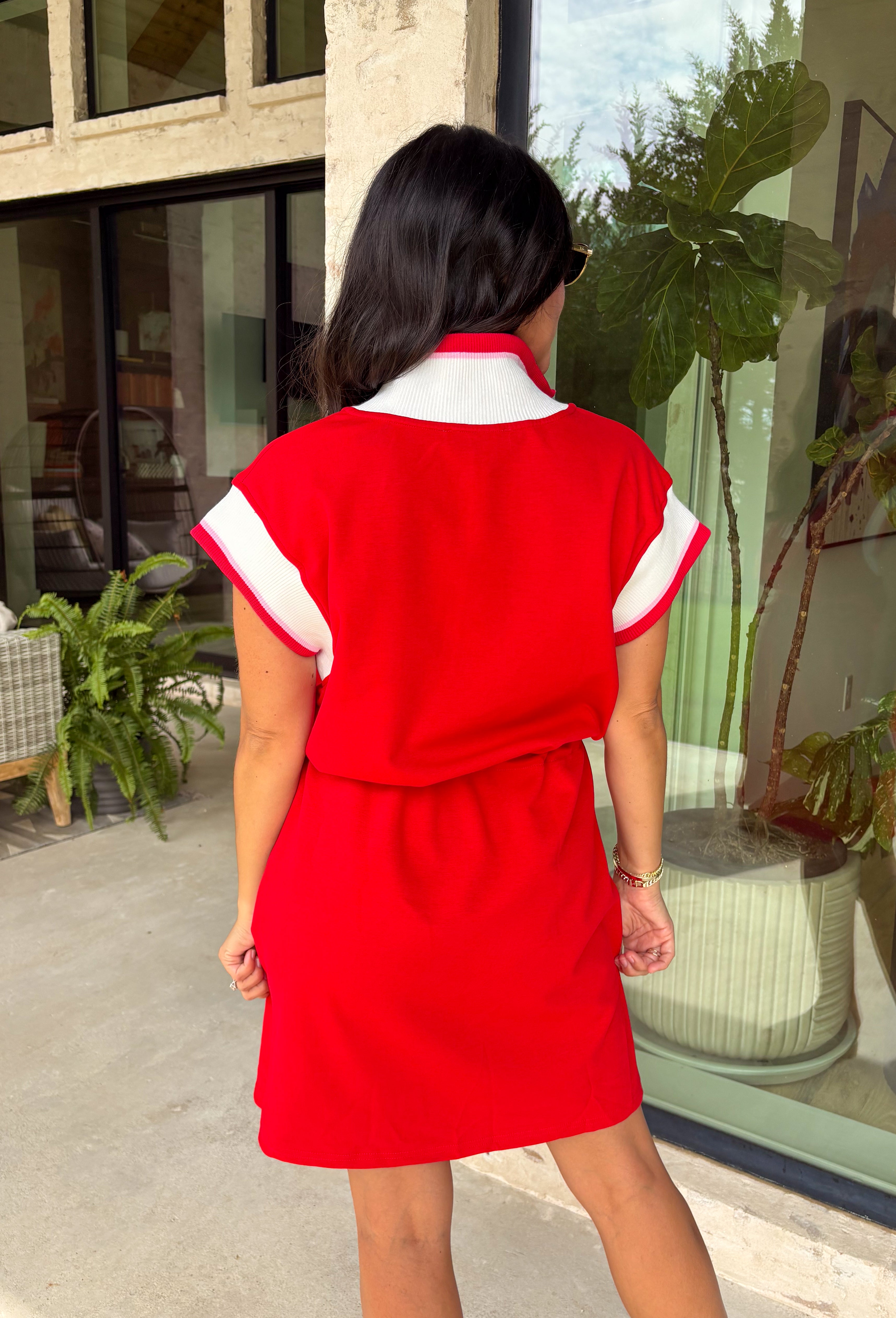 This red short sleeve dress is the perfect mix of sporty and cute for summer! Designed with a quarter zip neckline and elastic self-tie waist, it gives you that flattering, adjustable fit while keeping things comfortable for all-day wear. The red, pink, and white athletic stripe detail along the front, neckline, and cuffs adds a fun, energetic touch that makes this one stand out. Finished with side pockets (always a win), it’s perfect for everything from errands to casual plans.