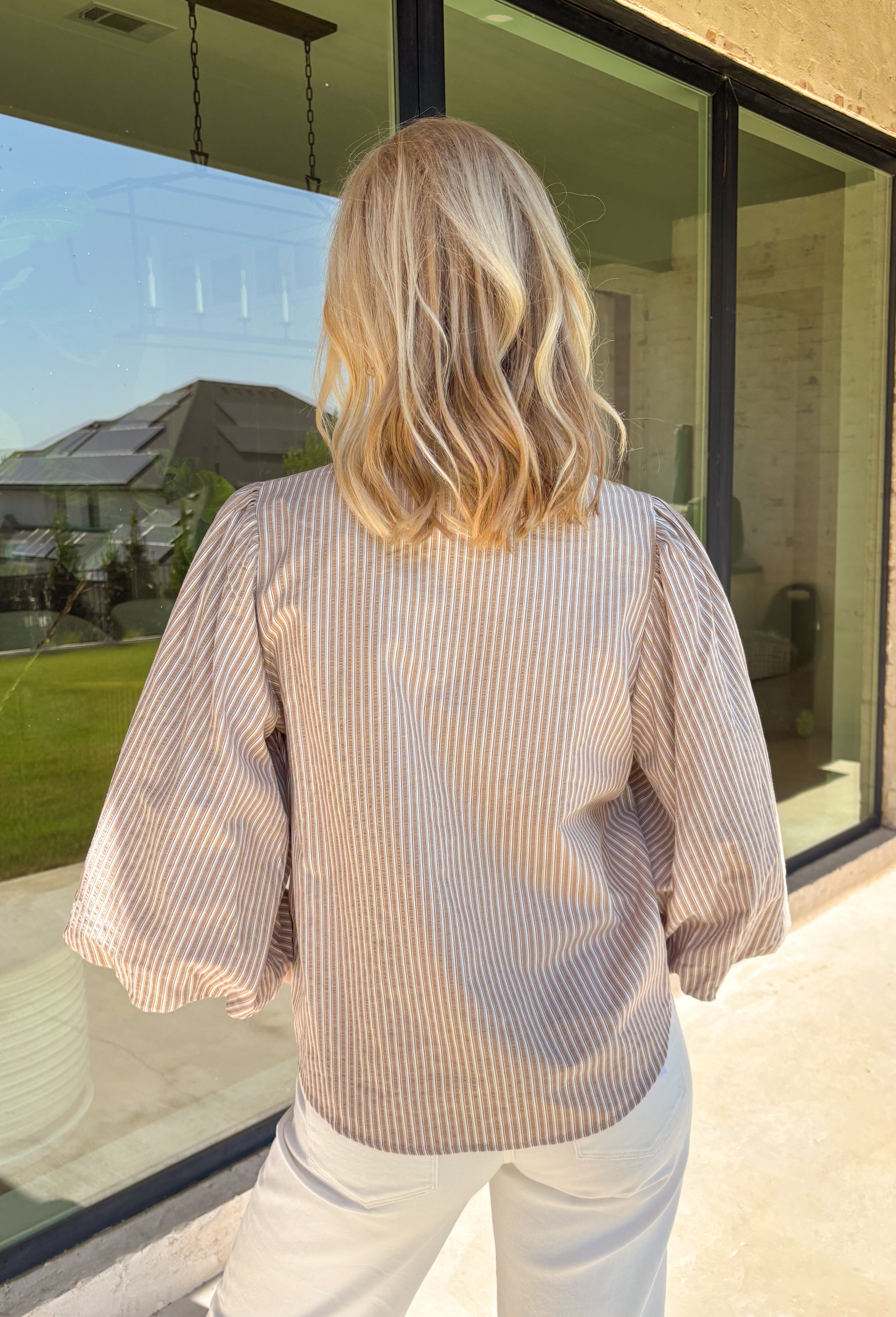 Classic stripes meet timeless style in this beautiful button-down blouse you'll reach for season after season. The soft tan and white striped print, feminine tie neckline, and billowy balloon sleeves create an effortlessly polished look that's perfect for the office, weekend brunch, or your favorite fall outings. Pair it with denim for a casual everyday look or tuck it into tailored trousers for an elevated outfit you'll love wearing all autumn long.