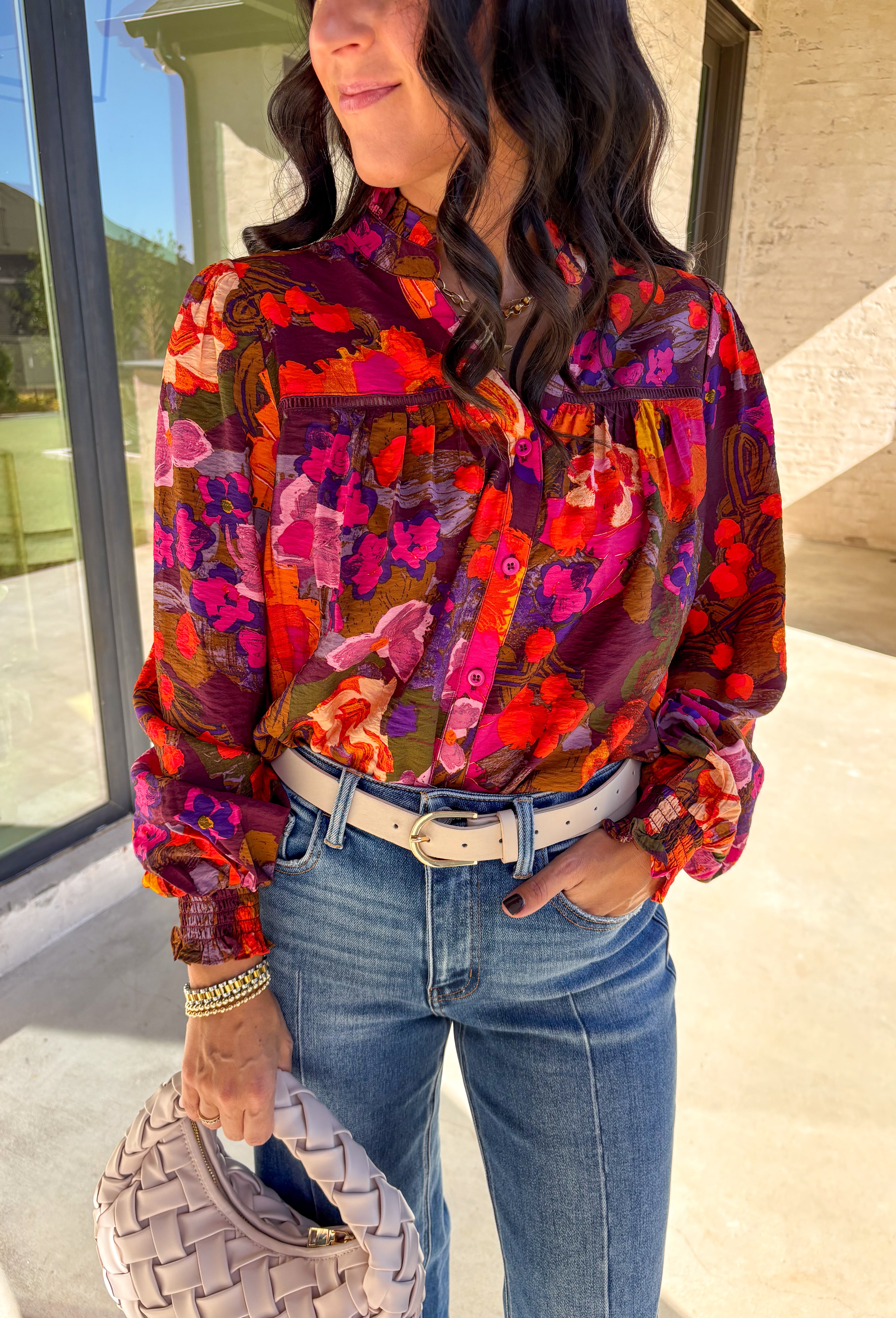 Brighten up your fall wardrobe with this stunning floral print top by Fate. Designed with long sleeves and a subtle ruffle neckline, this piece blends feminine details with bold color. The ladder lace trim across the top adds a touch of texture, while the smocked sleeves bring in a flattering finish. With shades of orange, purple, and pink throughout, this top perfectly balances playful color and everyday sophistication.