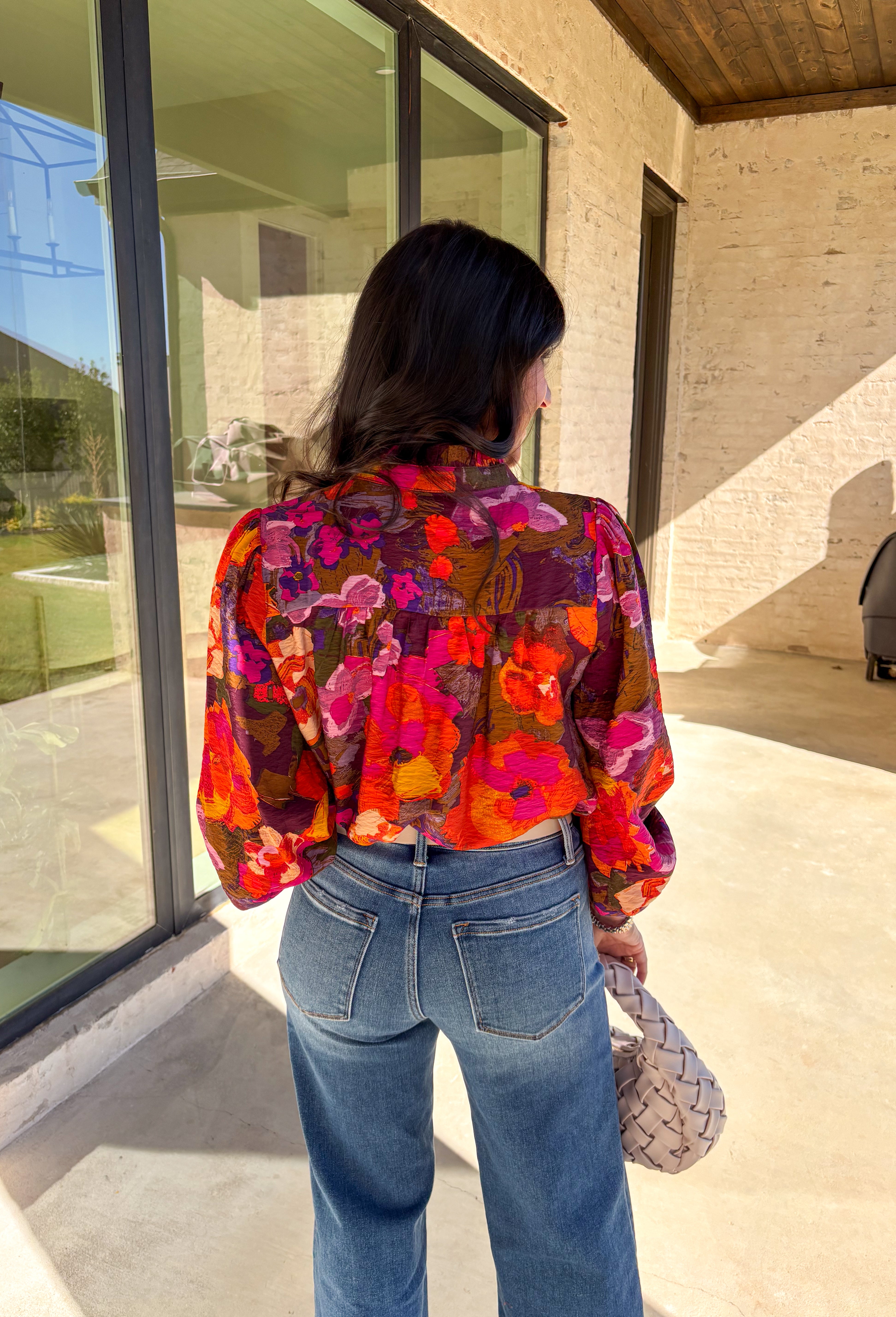 Brighten up your fall wardrobe with this stunning floral print top by Fate. Designed with long sleeves and a subtle ruffle neckline, this piece blends feminine details with bold color. The ladder lace trim across the top adds a touch of texture, while the smocked sleeves bring in a flattering finish. With shades of orange, purple, and pink throughout, this top perfectly balances playful color and everyday sophistication.