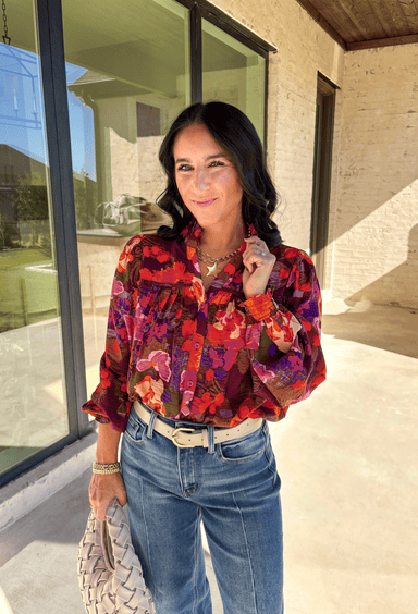 Brighten up your fall wardrobe with this stunning floral print top by Fate. Designed with long sleeves and a subtle ruffle neckline, this piece blends feminine details with bold color. The ladder lace trim across the top adds a touch of texture, while the smocked sleeves bring in a flattering finish. With shades of orange, purple, and pink throughout, this top perfectly balances playful color and everyday sophistication.