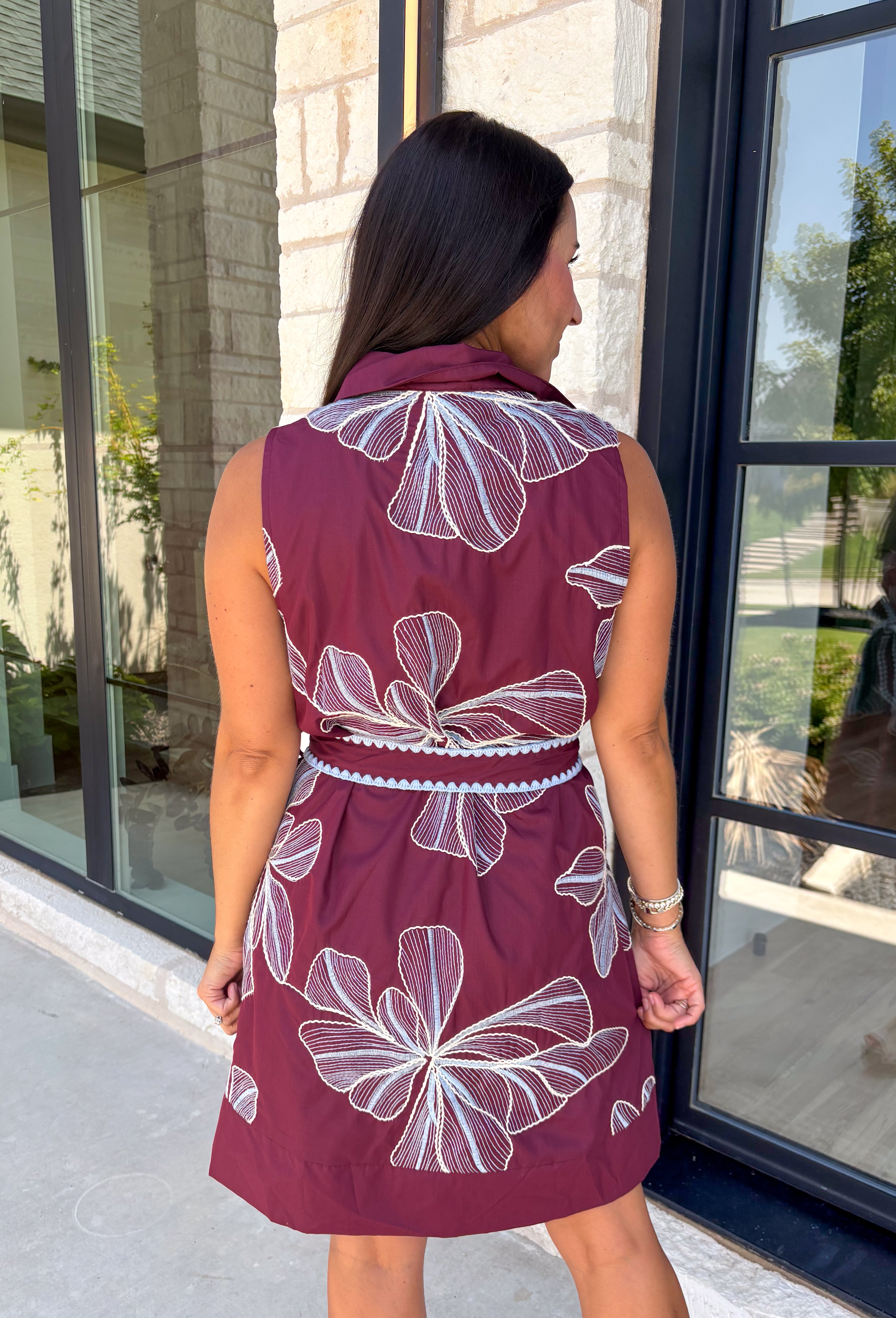Rich fall colors and beautiful embroidered details make this dress an instant seasonal favorite! Crafted in a gorgeous wine hue, this sleeveless dress features delicate light blue and off white floral embroidery that creates a charming, handcrafted look. The button front and self-tie waist belt with playful contrast pom trim create a flattering silhouette, while side pockets and a fully lined design make it as practical as it is beautiful. 