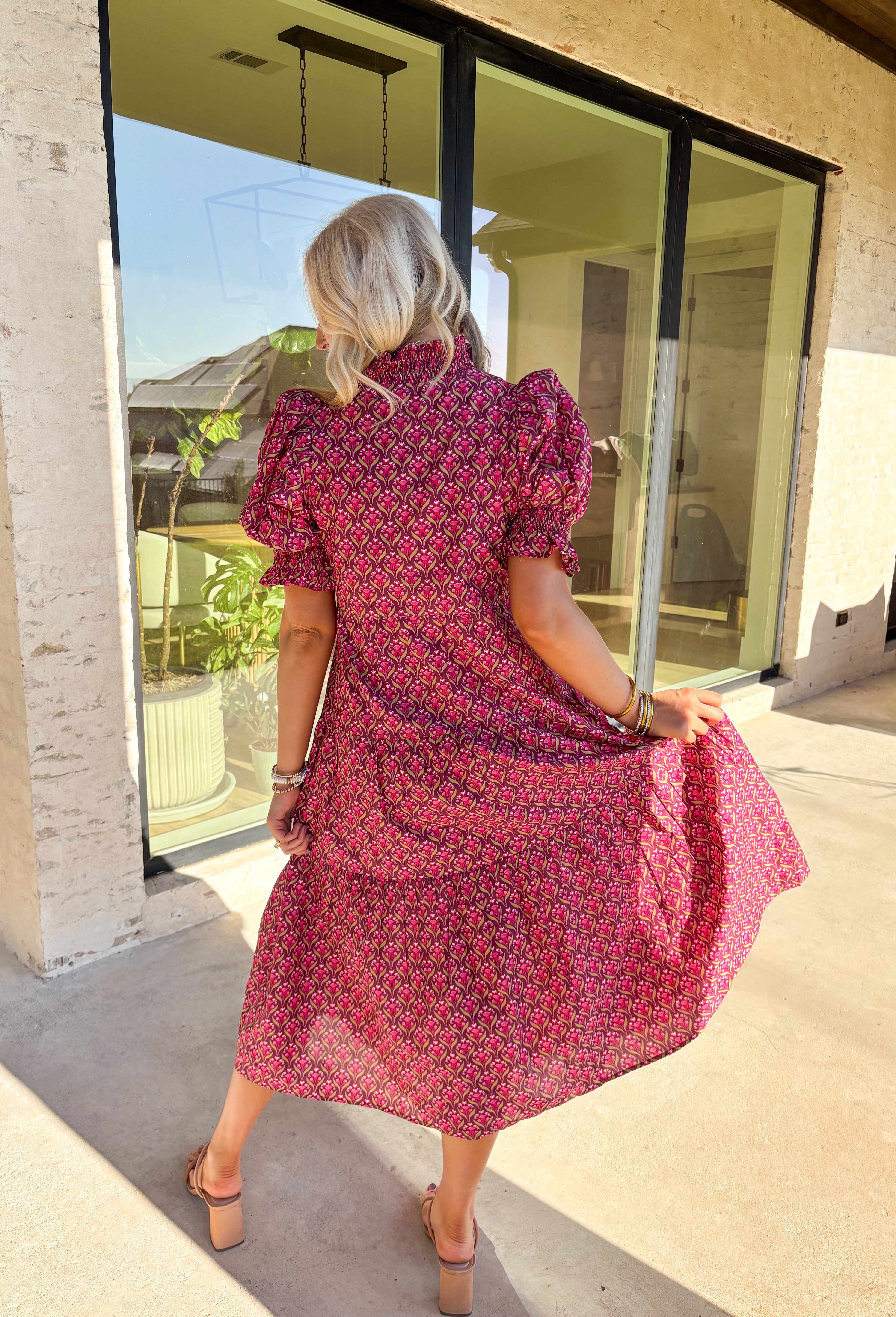 Romantic florals meet effortless style in this puff sleeve midi dress by Entro. Set against a rich burgundy background, the botanical print features shades of pink with subtle pops of olive for a seasonal feel. A split neckline trimmed in contrast detailing adds a polished touch, while smocked cuffs and a smocked collar bring in texture and comfort. Side pockets and a full lining make this dress as practical as it is beautiful, perfect for everything from special occasions to fall gatherings.