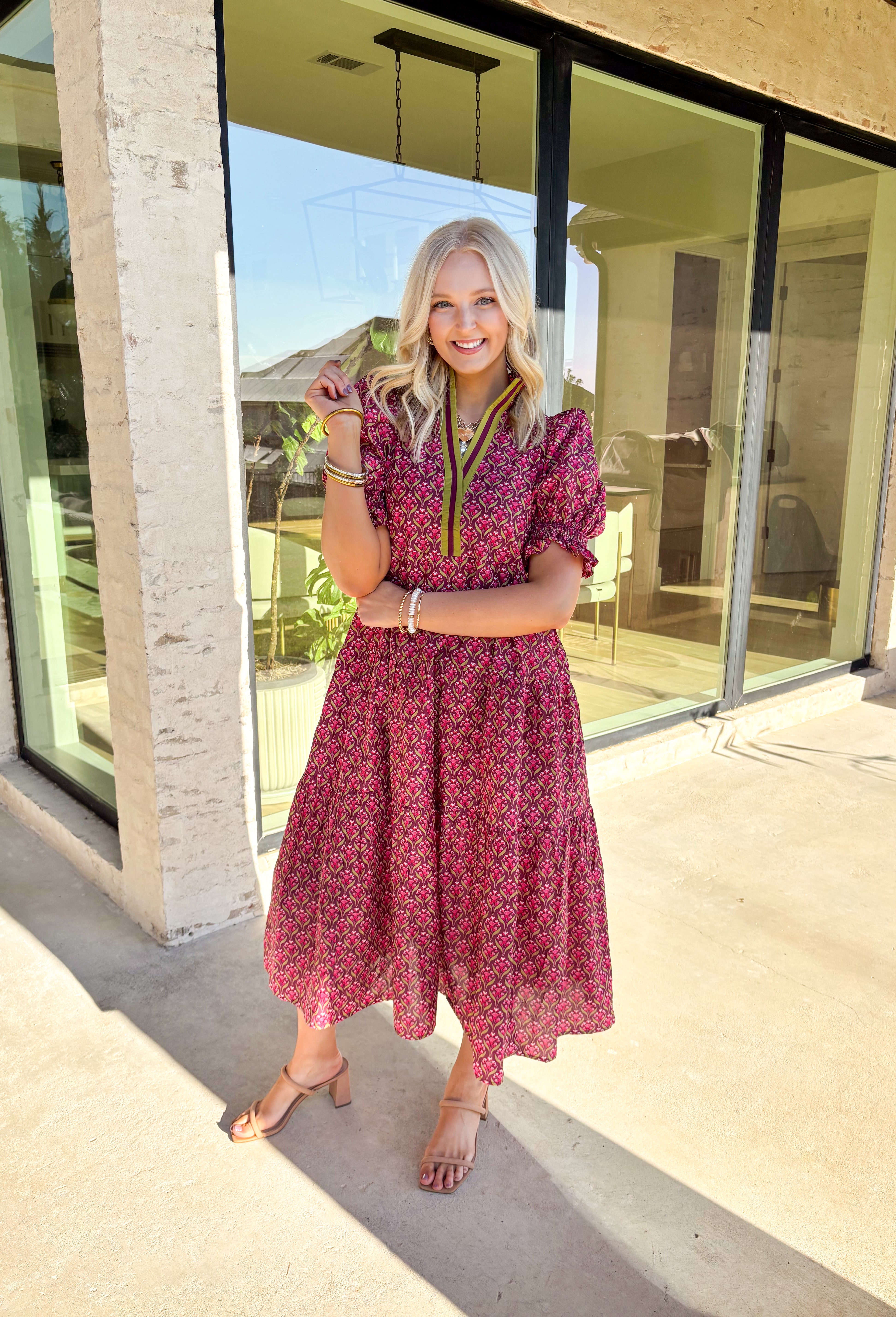 Romantic florals meet effortless style in this puff sleeve midi dress by Entro. Set against a rich burgundy background, the botanical print features shades of pink with subtle pops of olive for a seasonal feel. A split neckline trimmed in contrast detailing adds a polished touch, while smocked cuffs and a smocked collar bring in texture and comfort. Side pockets and a full lining make this dress as practical as it is beautiful, perfect for everything from special occasions to fall gatherings.