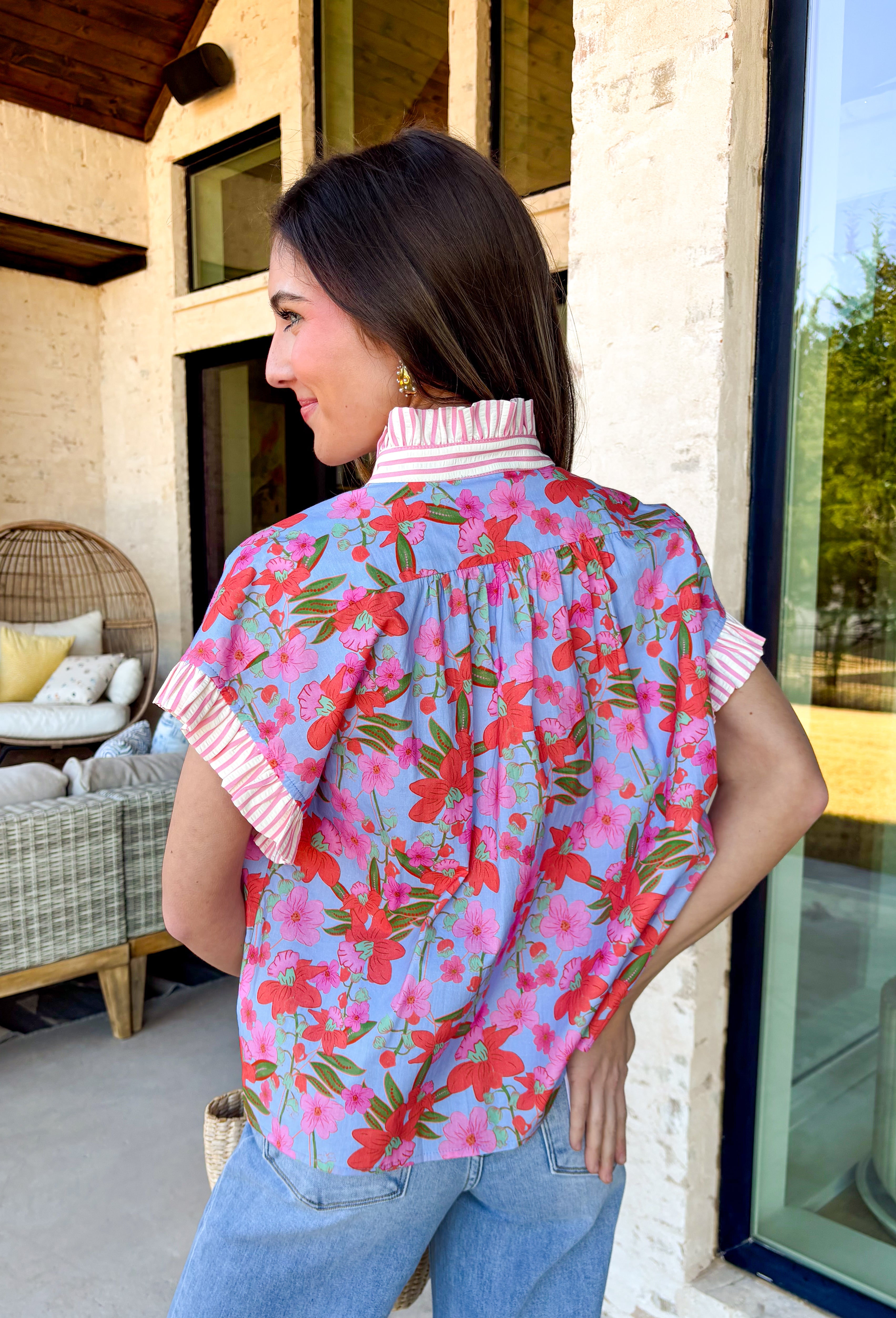 This light blue short sleeve top by Entro is basically spring in top form. With its colorful floral print in bright pops of red, pink, and green, it’s the kind of piece that instantly makes your outfit feel fun, fresh, and happy. The button-down front keeps it classic and easy to style, while the pink and cream striped ruffle neckline and matching sleeve cuffs add the cutest little contrast.&nbsp;It’s lightweight, breathable, and perfect for those sunny days when you want to look put-together without overth