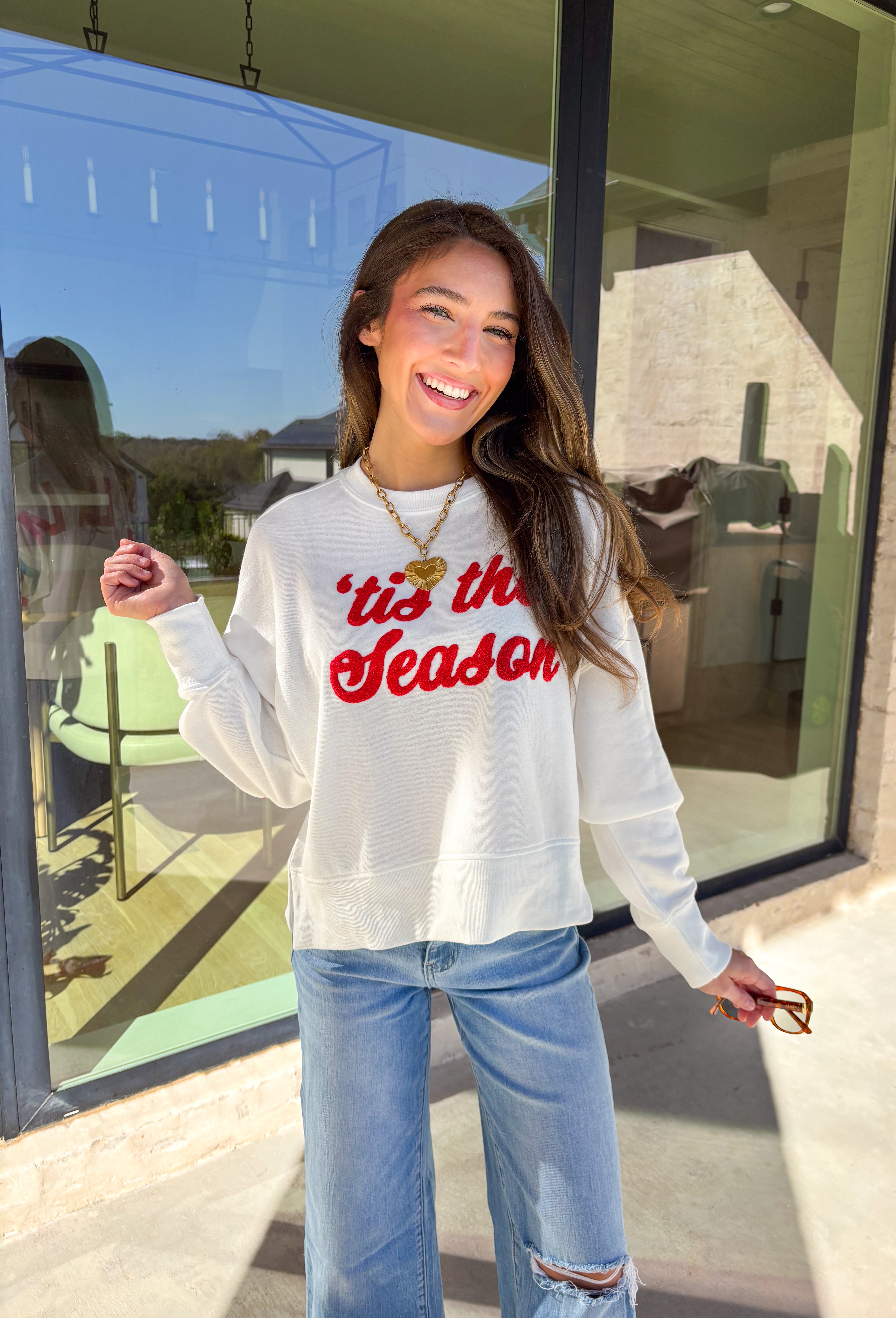Get in the holiday spirit with this cheerful white pullover by Shiraleah! The front features a textured red “‘Tis The Season” design, while the back adds a playful surprise with a colorful “Fa La La” print. Its soft fabric and cropped fit make it the perfect piece for decking the halls or cozy nights by the fire.