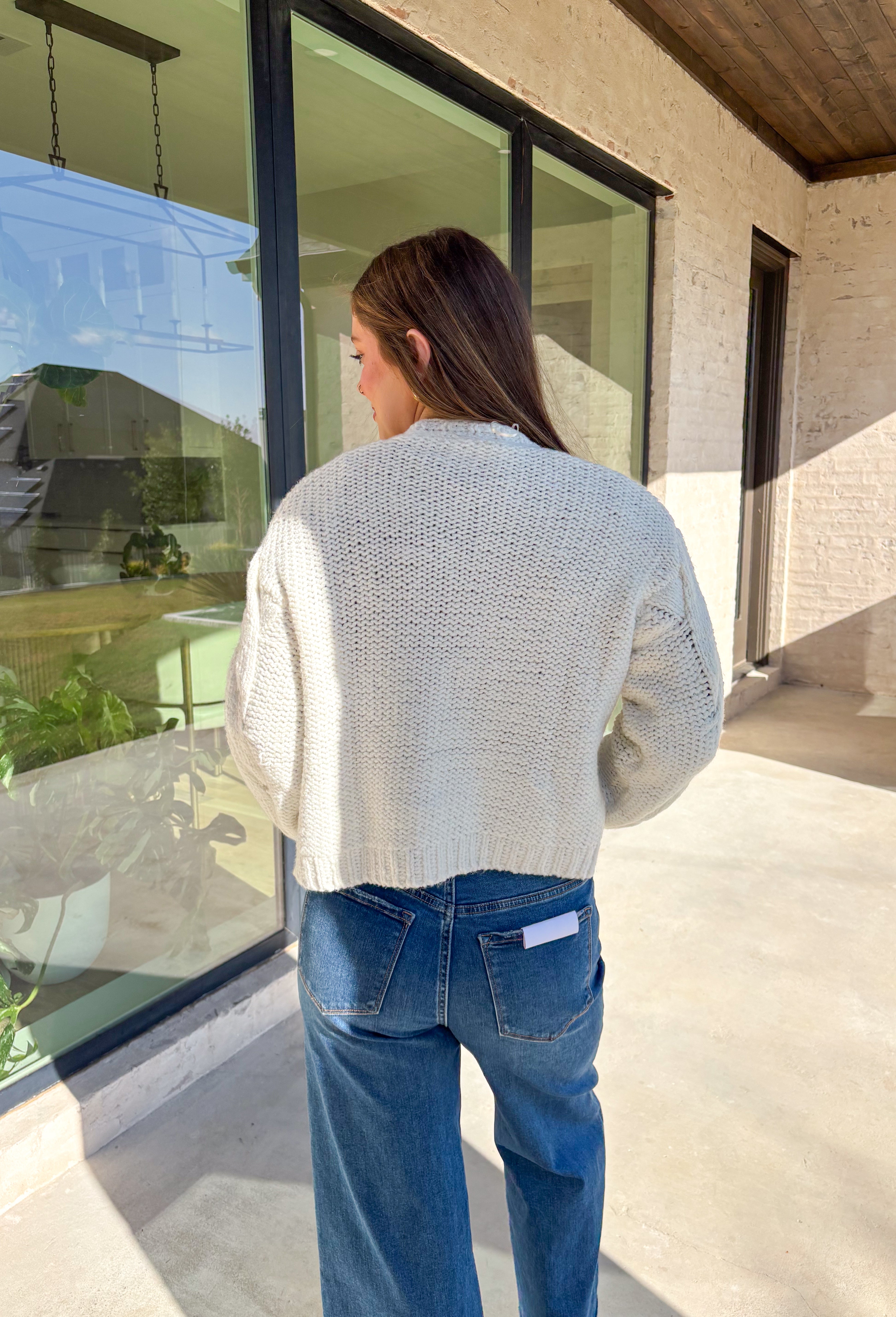 Cozy up in this off-white open-front cardigan by Double Zero. Designed with a chunky cable knit texture, this cardigan is the perfect layering piece for crisp fall days. The relaxed fit and soft feel make it a versatile staple you’ll reach for again and again—whether you’re styling it over a dress or pairing it with jeans and a tee.