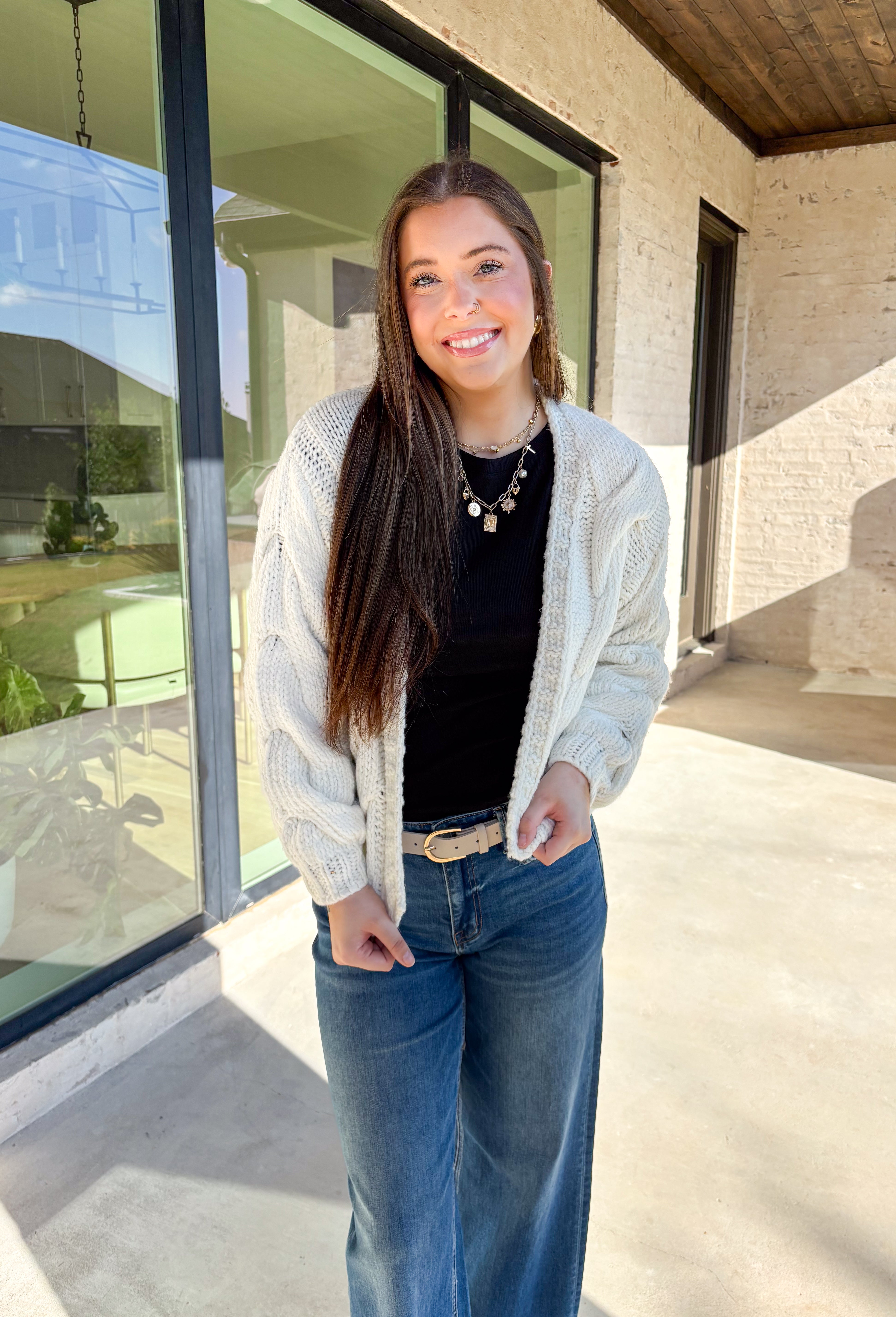 Cozy up in this off-white open-front cardigan by Double Zero. Designed with a chunky cable knit texture, this cardigan is the perfect layering piece for crisp fall days. The relaxed fit and soft feel make it a versatile staple you’ll reach for again and again—whether you’re styling it over a dress or pairing it with jeans and a tee.