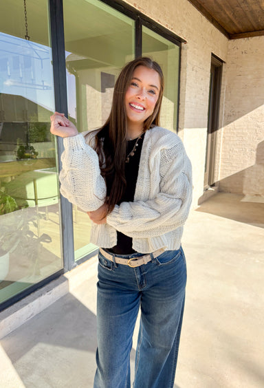 Cozy up in this off-white open-front cardigan by Double Zero. Designed with a chunky cable knit texture, this cardigan is the perfect layering piece for crisp fall days. The relaxed fit and soft feel make it a versatile staple you’ll reach for again and again—whether you’re styling it over a dress or pairing it with jeans and a tee.