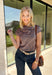 Add a fresh take on classic fall plaid to your wardrobe with this brown micro plaid top from Current Air. The draped cowl neckline creates a soft gathered effect that gives the silhouette a little extra interest without feeling overdone. A ribbed backing adds an unexpected mix of texture, while the warm brown plaid makes it easy to pair with all your favorite autumn neutrals. Wear it with trousers for a put-together office look, then swap in denim and boots when the weekend rolls around.