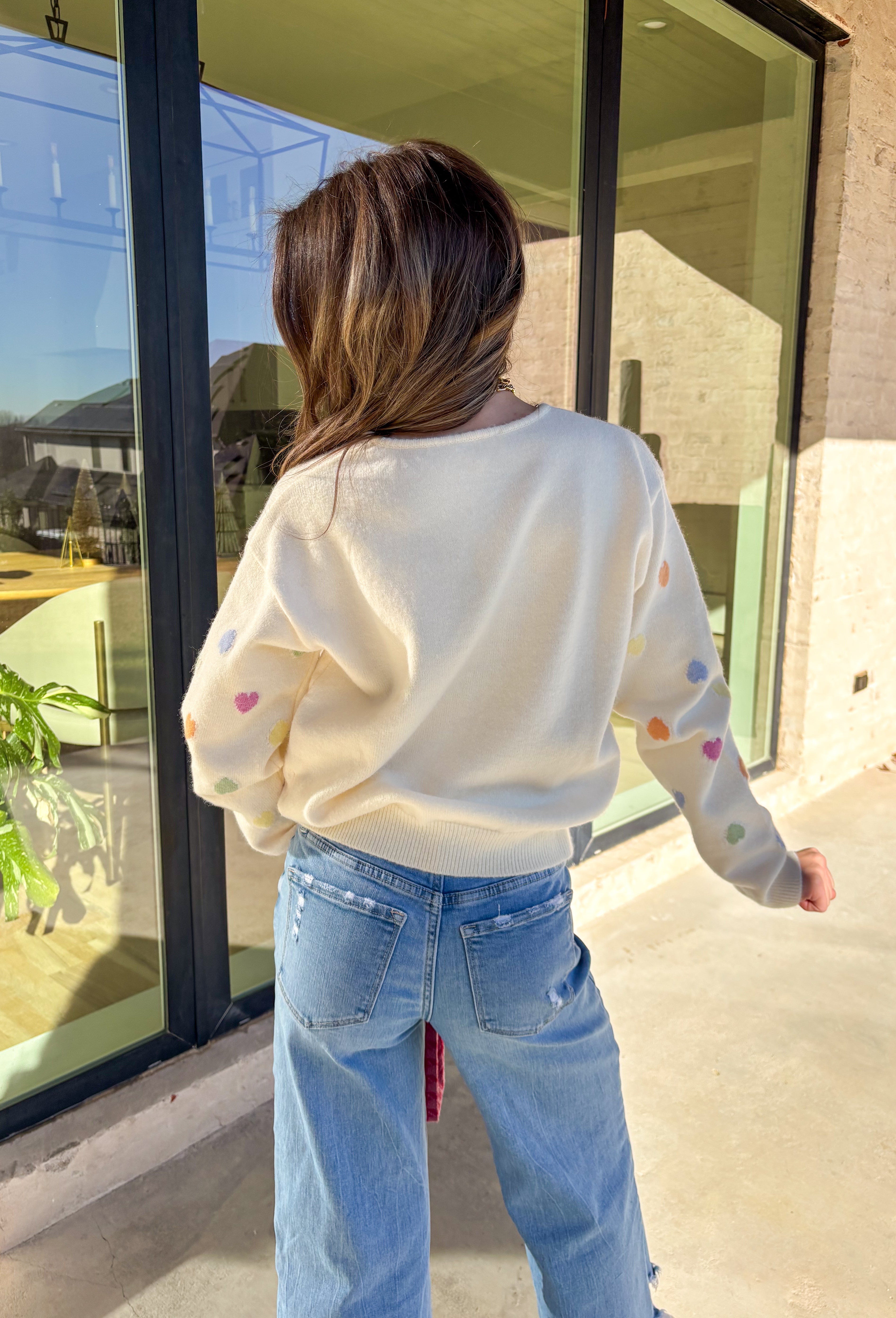 Sweet, cheerful, and full of love, this cream sweater by Sunday Edition is perfect for Valentine’s Day and beyond. Featuring a colorful heart print in shades of orange, pink, yellow, green, and blue, this cozy knit brings a fun pop of color to your wardrobe. Soft and lightweight with an easy fit, it’s the kind of sweater that feels festive for February but still cute all season long.