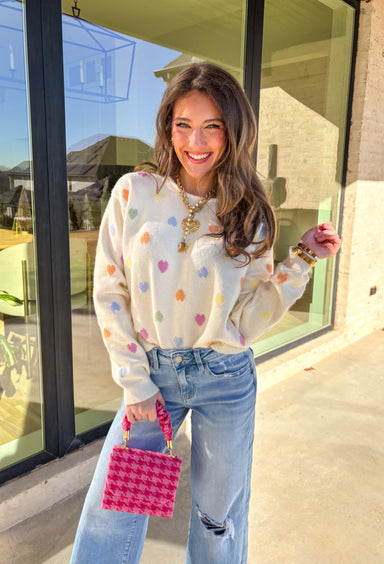 Sweet, cheerful, and full of love, this cream sweater by Sunday Edition is perfect for Valentine’s Day and beyond. Featuring a colorful heart print in shades of orange, pink, yellow, green, and blue, this cozy knit brings a fun pop of color to your wardrobe. Soft and lightweight with an easy fit, it’s the kind of sweater that feels festive for February but still cute all season long.