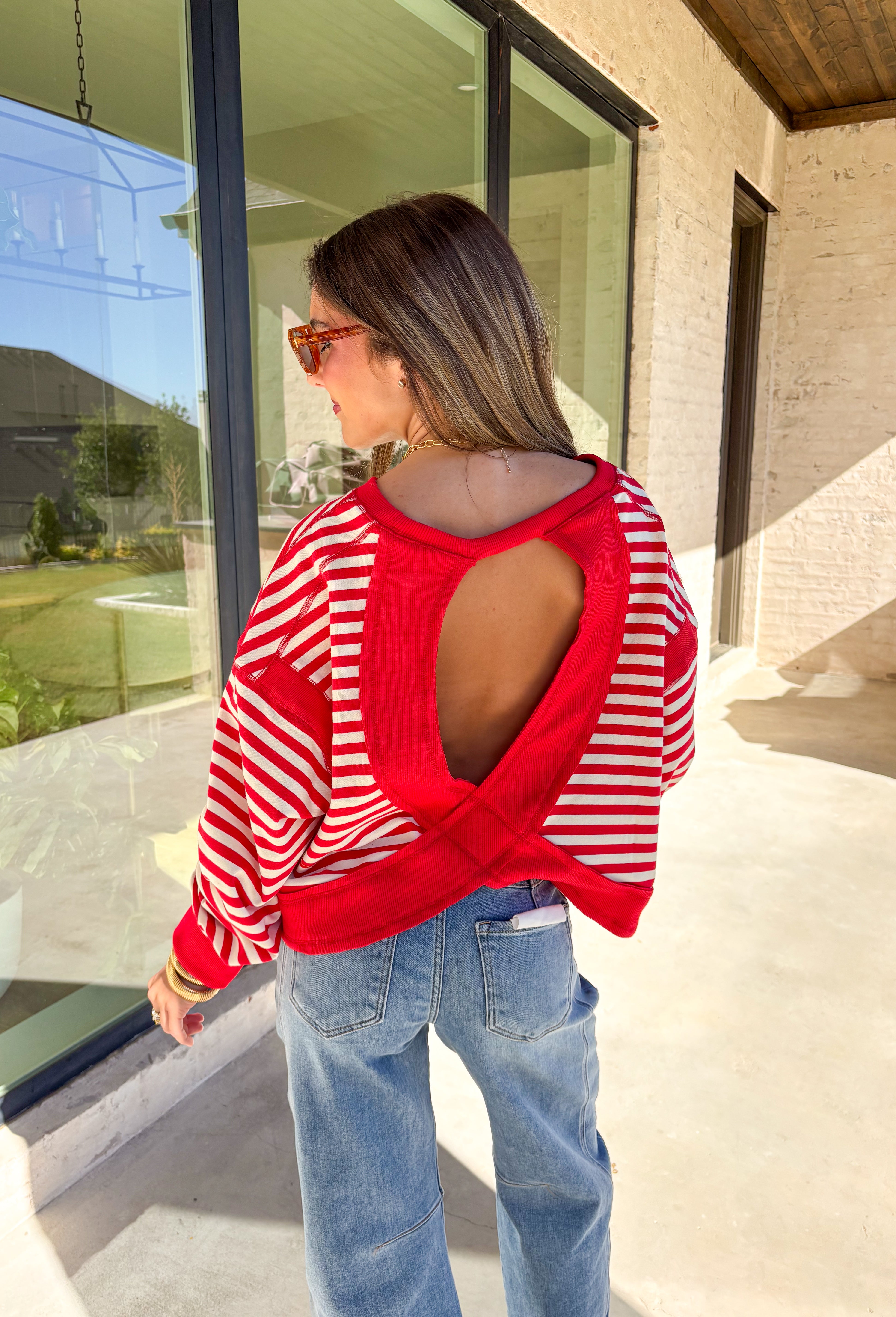 A classic stripe with a flirty twist—this red and ivory long sleeve top by Rae Mode is perfect for cozy yet stylish days. The open-back design adds a fun surprise, while the solid red detailing on the cuffs, sleeve centers, and neckline gives it a bold pop. Crafted from a soft, stretchy fabric blend, it’s the ultimate mix of comfort and statement style for the season.